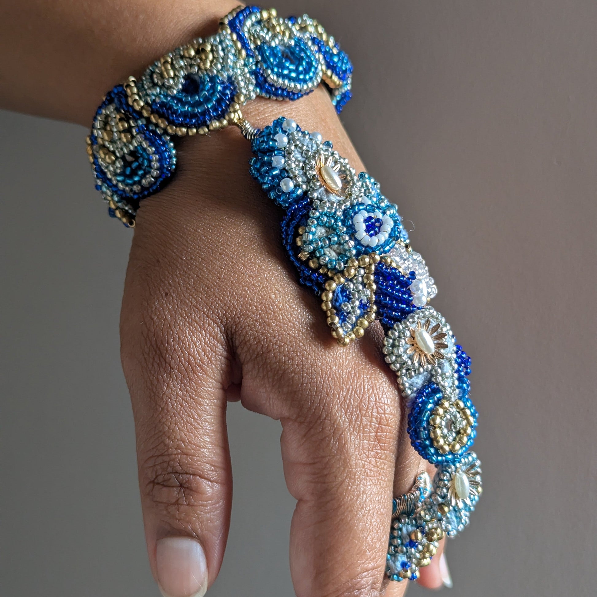 Nira 5-in-1 worn with fingers pointing down - showing full length of blue, white and gold Indian hand bracelet.