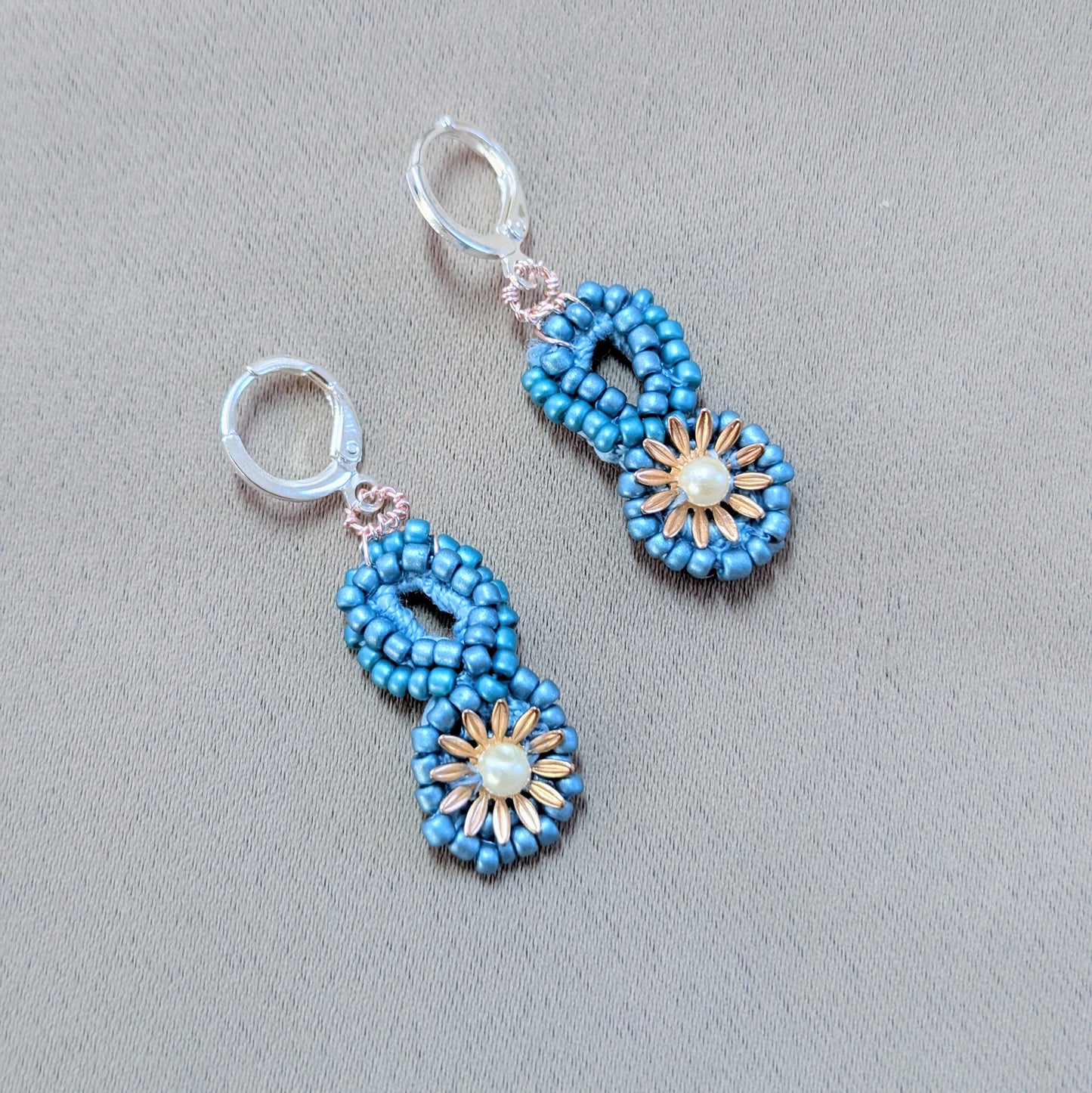 Close-up of Tara earrings showing intricate crochet beadwork and gold-plated floral detailing.