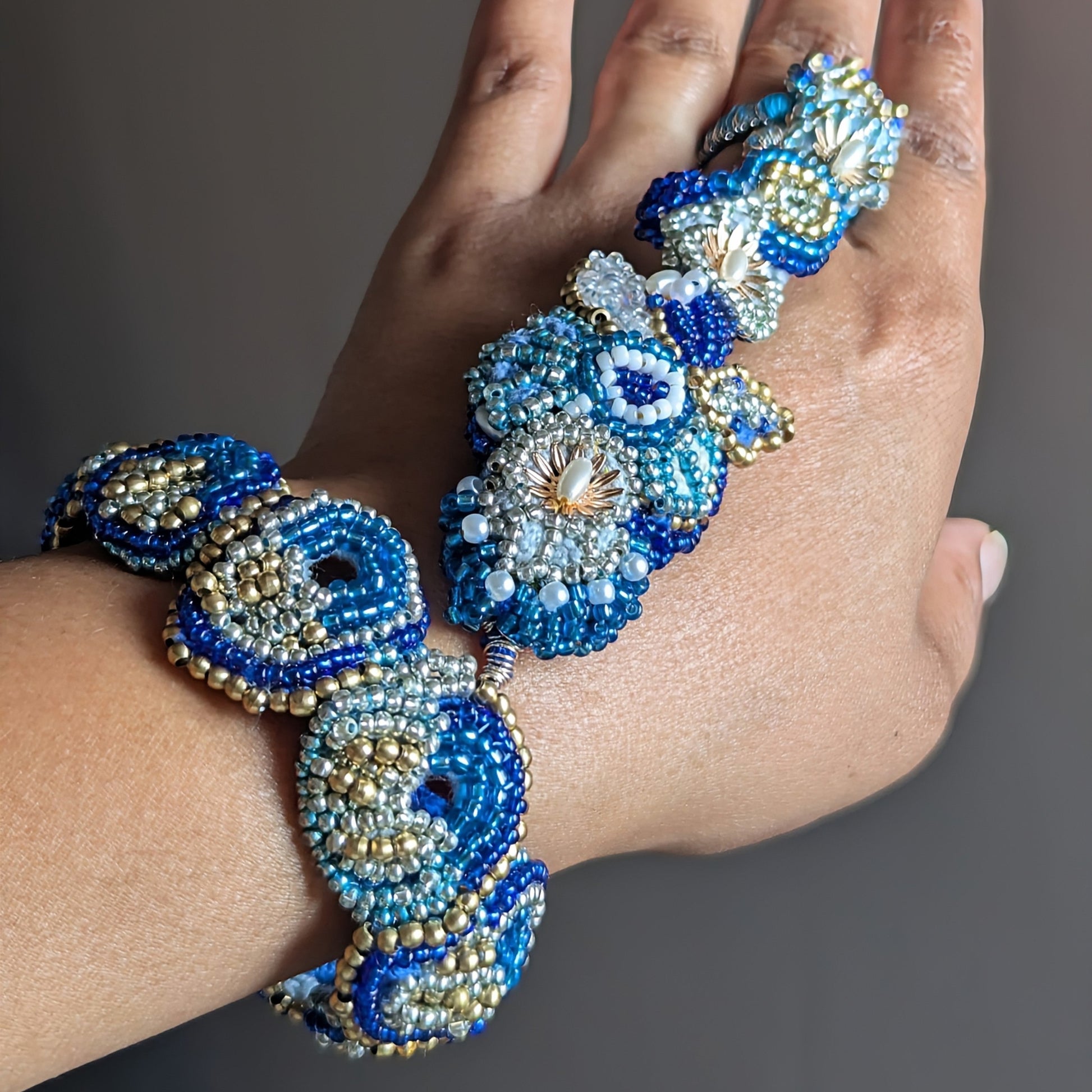 Nira 5-in-1 Indian haath phool worn flat on hand fingers pointing up showing the full length of blue and gold hand piece.