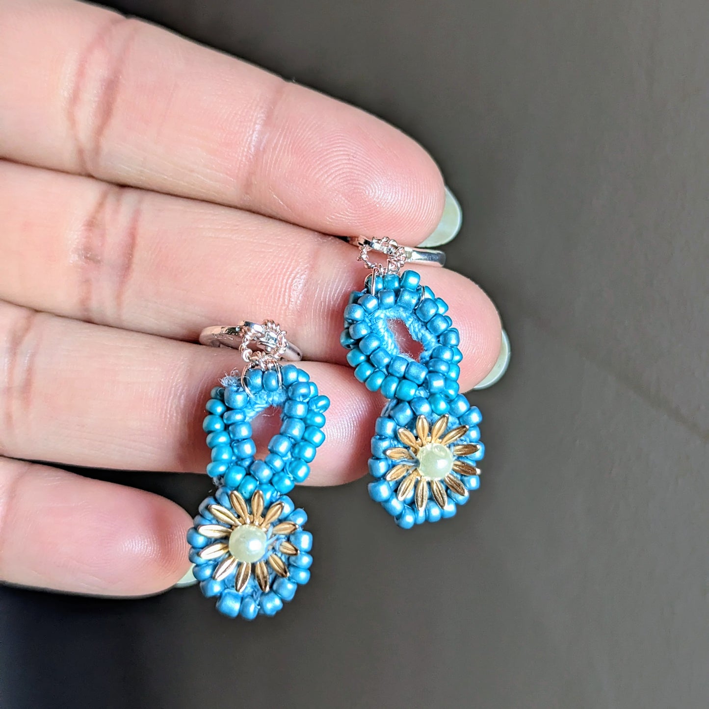 Pair of Tara earrings displayed on neutral background highlighting their celestial blue and gold design.