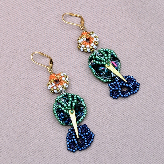 A handcrafted pair of Indian-inspired blue, green, white, gold and orange beaded earrings exclusive to Mayaani Jewellery. Featuring sustainably handcrafted scrap beads making use of waste produced during the jewellery making process.