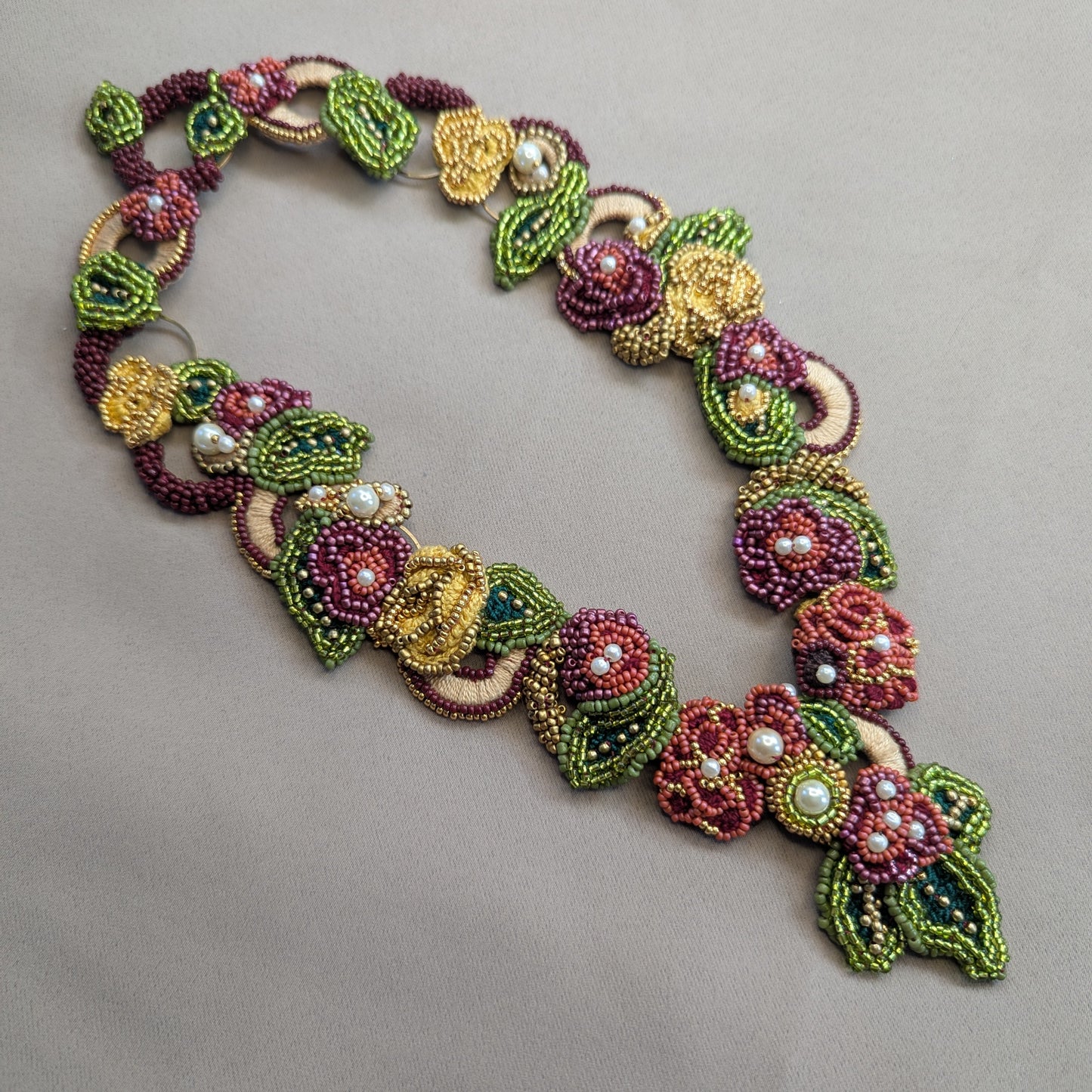 Rukmini botanical bead necklace flat lay - handmade in the UK by Mayaani Jewellery in burgundy, olive and gold.