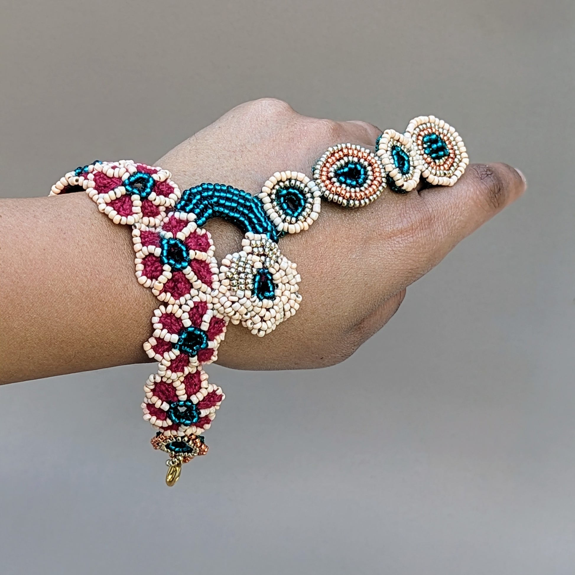 Neha Collection Indian bridal bracelet with intricate beadwork, crochet and wire wrapping in emerald, peach, red and gold tones, handmade in the UK for Mayaani Jewellery.