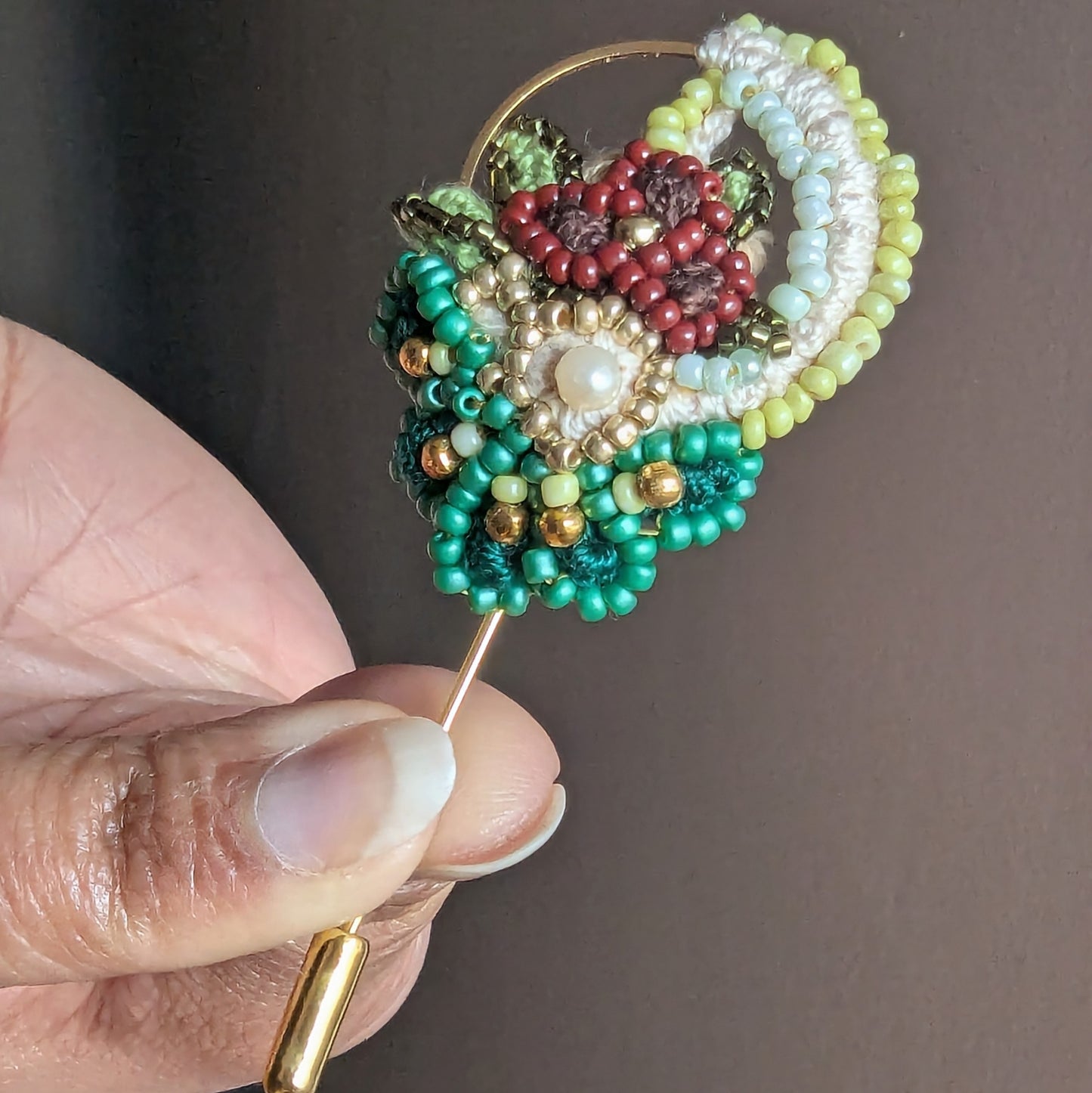 Front view of Sarika beaded brooch with coral and pearl bead embroidery framed by gold hoop.