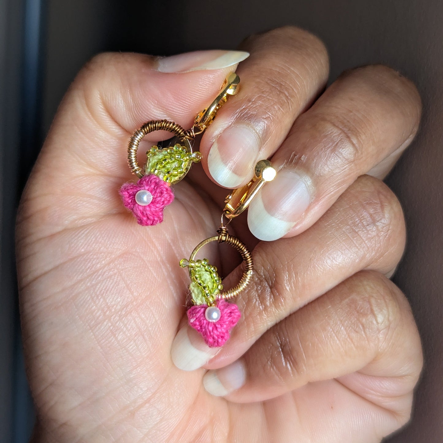 Close up view of a gold hoop pair of floral pink, chartreuse green, gold and pearl statement clip-on earrings exclusive to sustainable artisan luxury brand Mayaani UK.