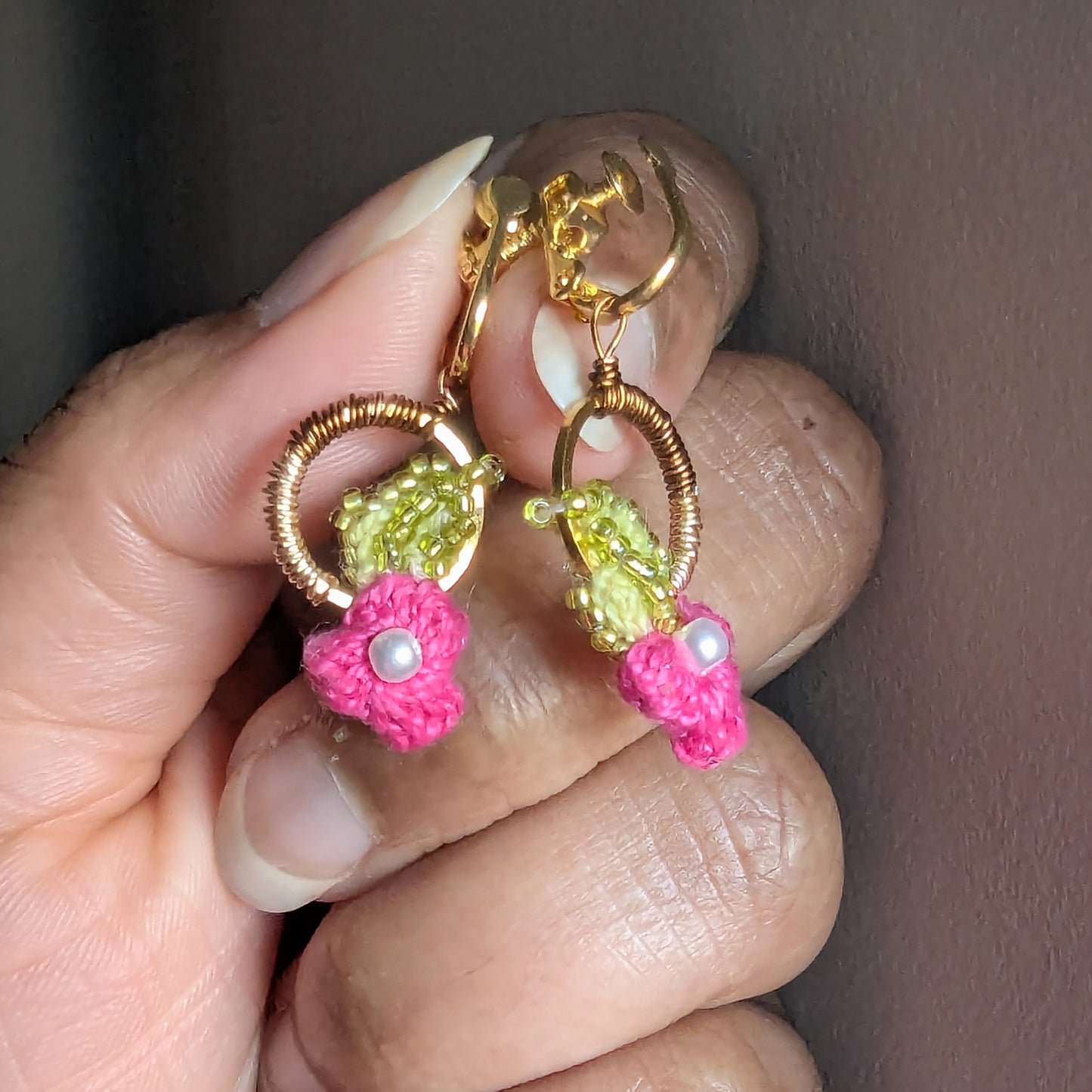 A close-up view of a comfortable, lightweight pair of gold, pink, green , pearl and bronze pair of botanical clip-on  Pallavi earrings by Mayaani Jewellery UK.