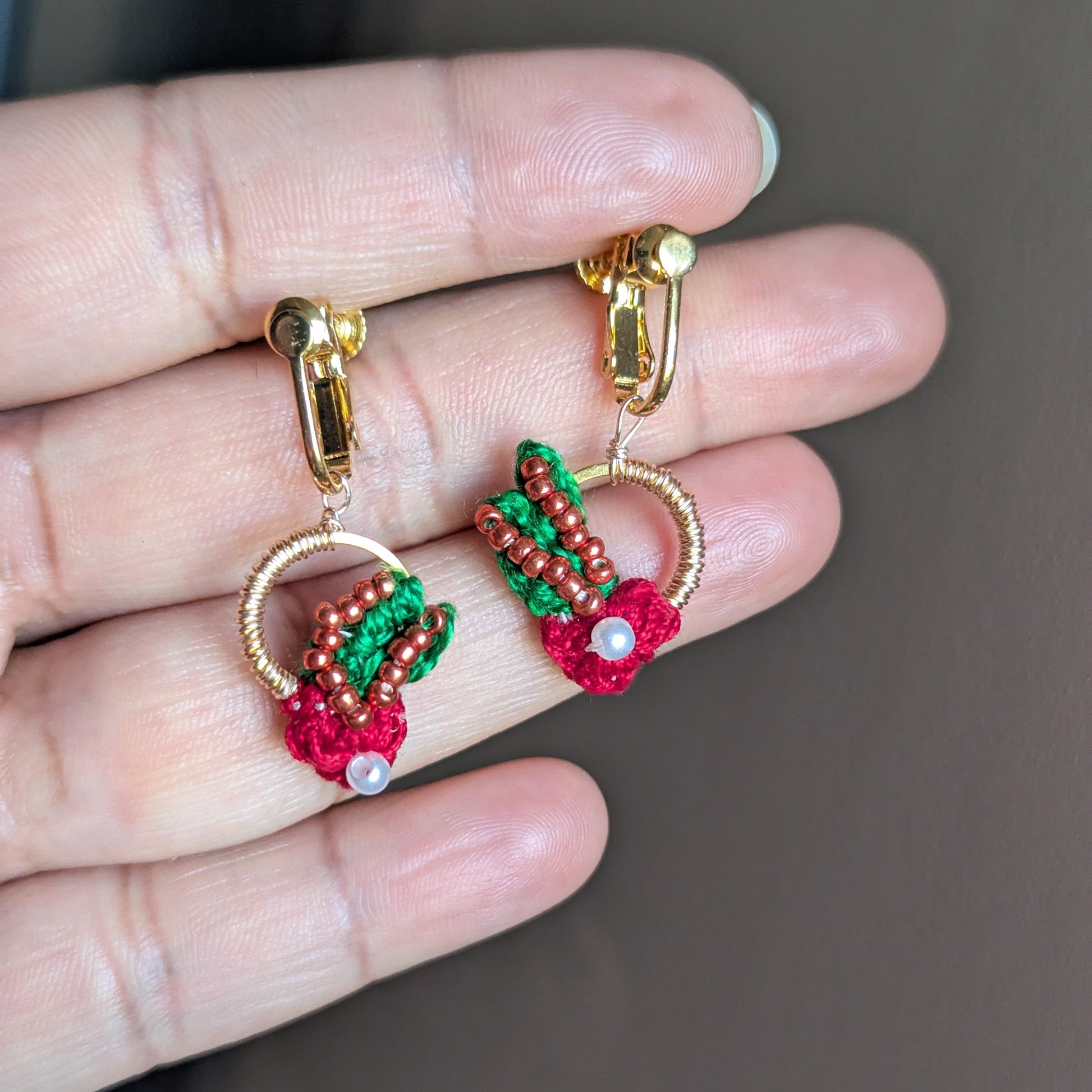 A pair of kumkum handcrafted comfortable screw back clip-on Mayaani Jewellery earrings in red, green, gold and copper with floral motifs and rose gold accents.
