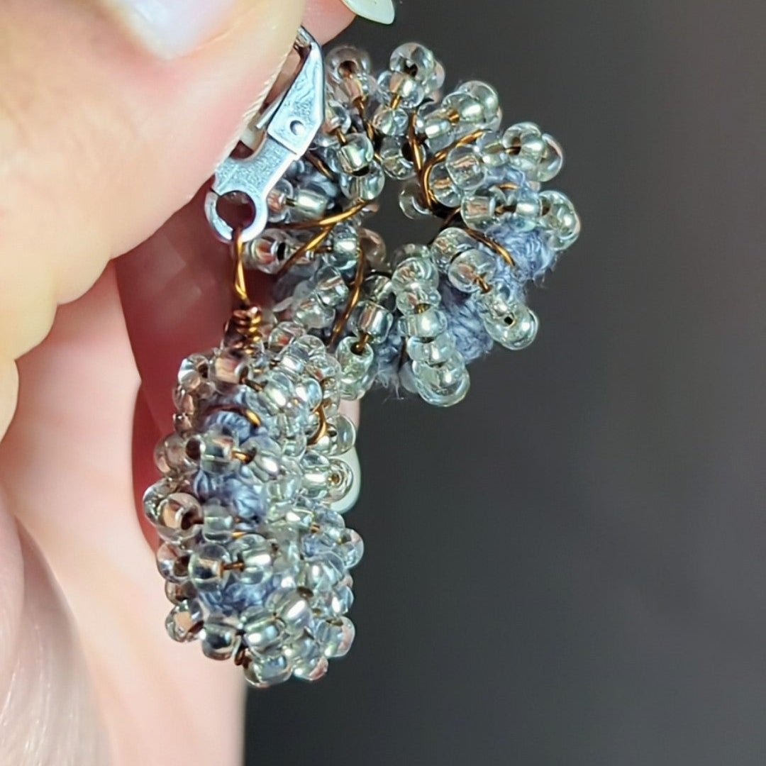 Close-up of artisan-made silver and grey seed bead earrings with stainless-steel clasps.
