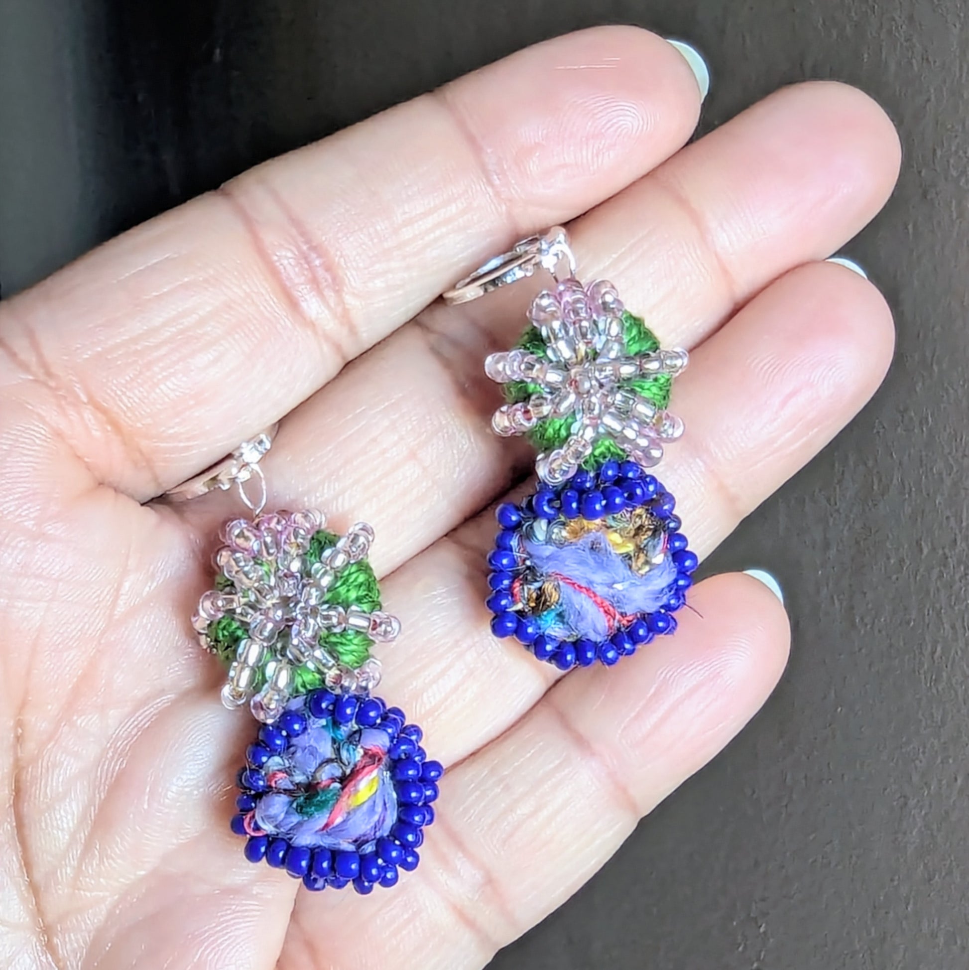 Gaia earrings resting on hand with natural light reflecting off Czech glass seed beads and upcycled centre bead.