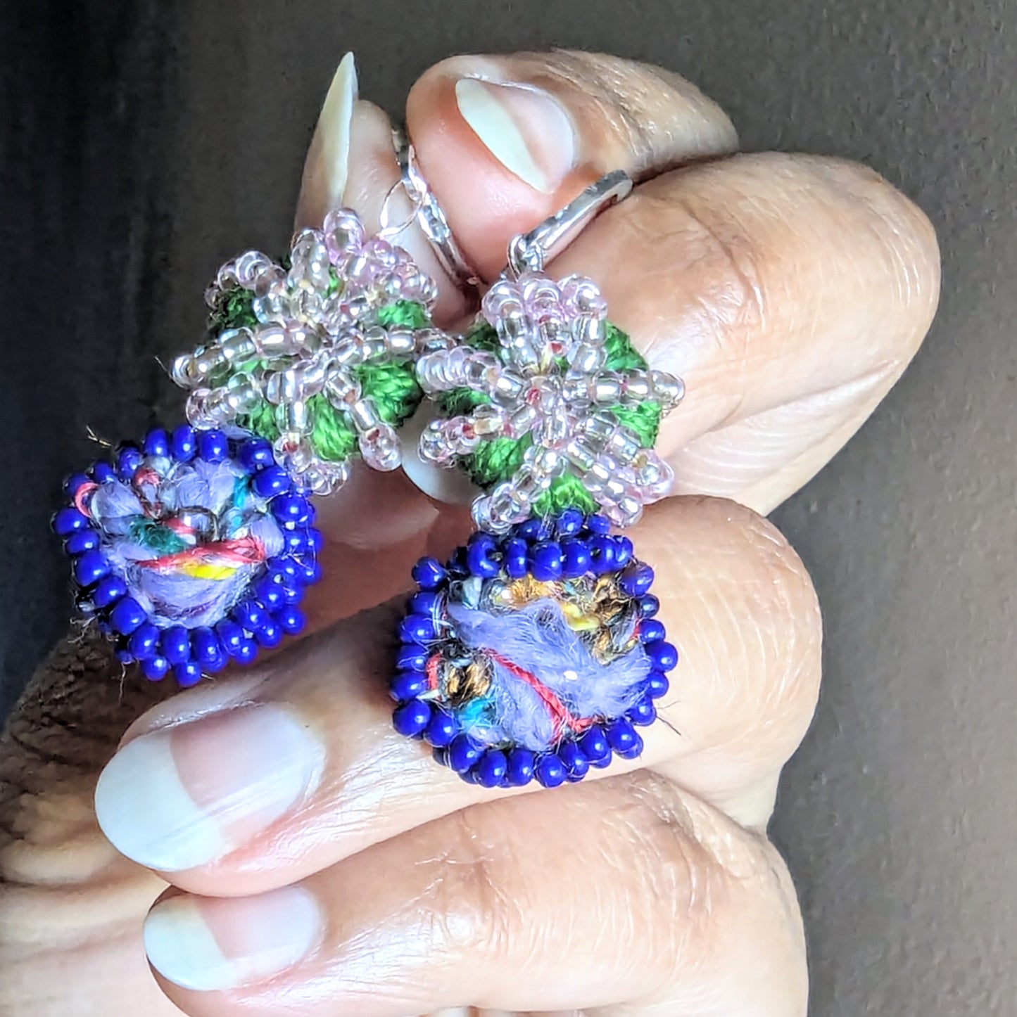 Detailed view of green and pink crochet beadwork around blue glass centre in Gaia earrings.
