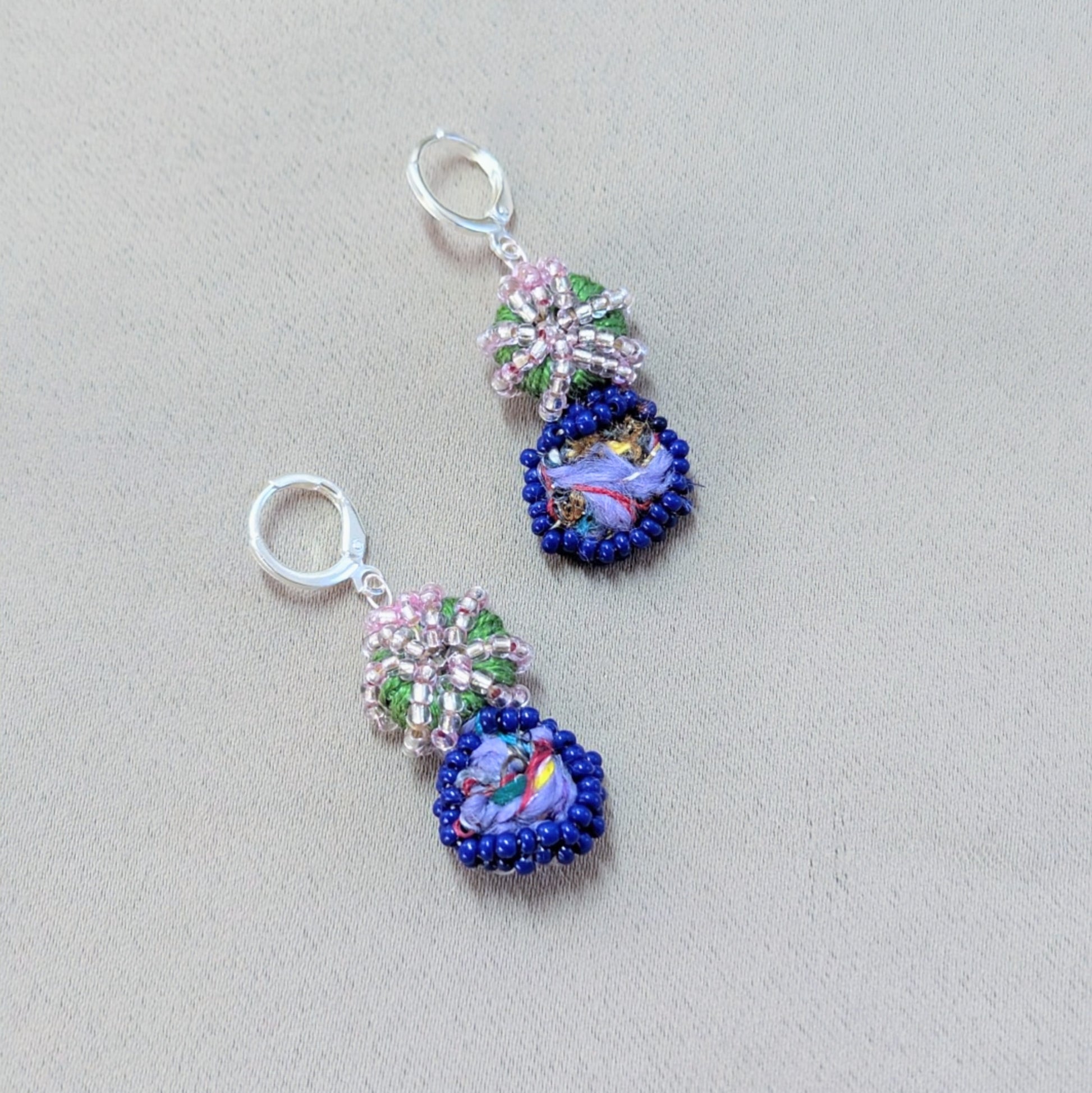 Close-up of Gaia earrings highlighting intricate bead embroidery and sterling-silver clasps.