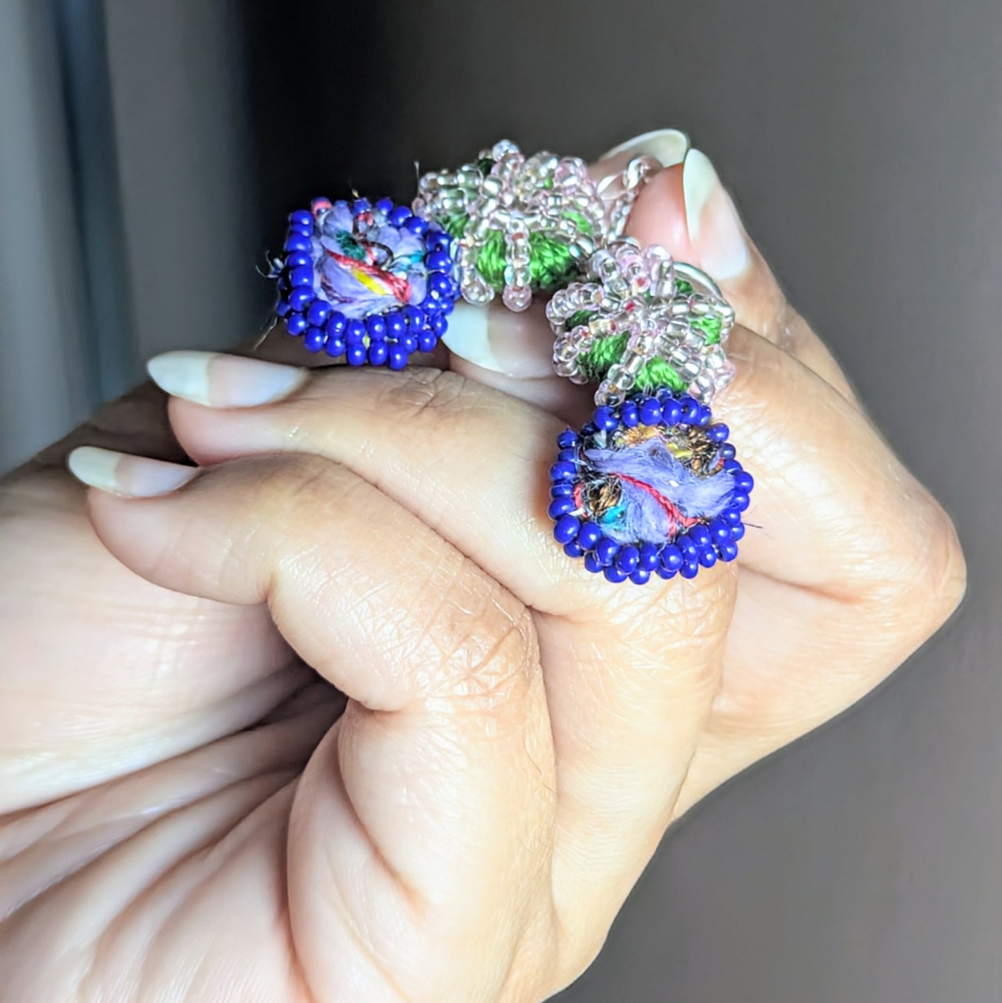 Handcrafted Gaia earrings illuminated under natural light, showing green cotton crochet and gold-bronze undertones.