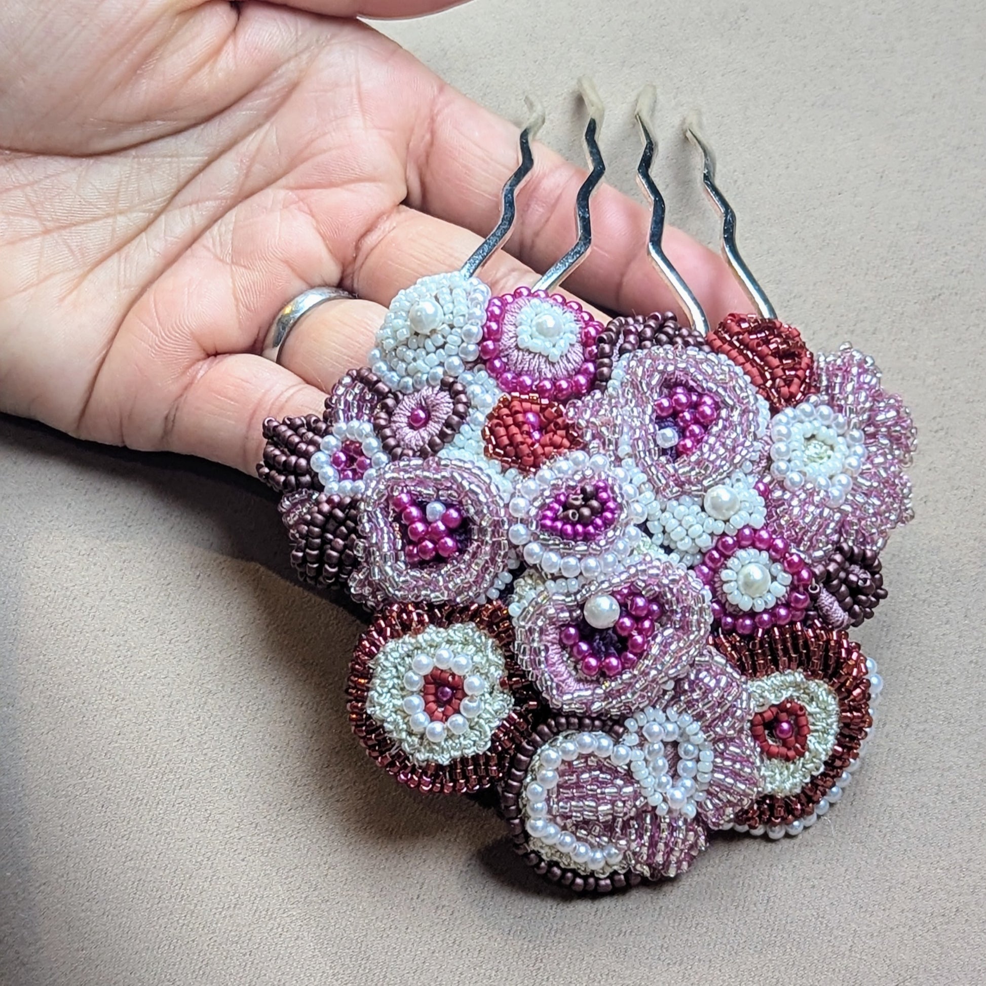 Handcrafted Indian bridal hair pin from the 'Gulab Rani' jewellery set by Mayaani Jewellery, featuring stainless steel prongs intricately hand-beaded floral motifs. Designed with concentric circles and adorned with pearl seed beads in shades of red, pink, purple and ivory.