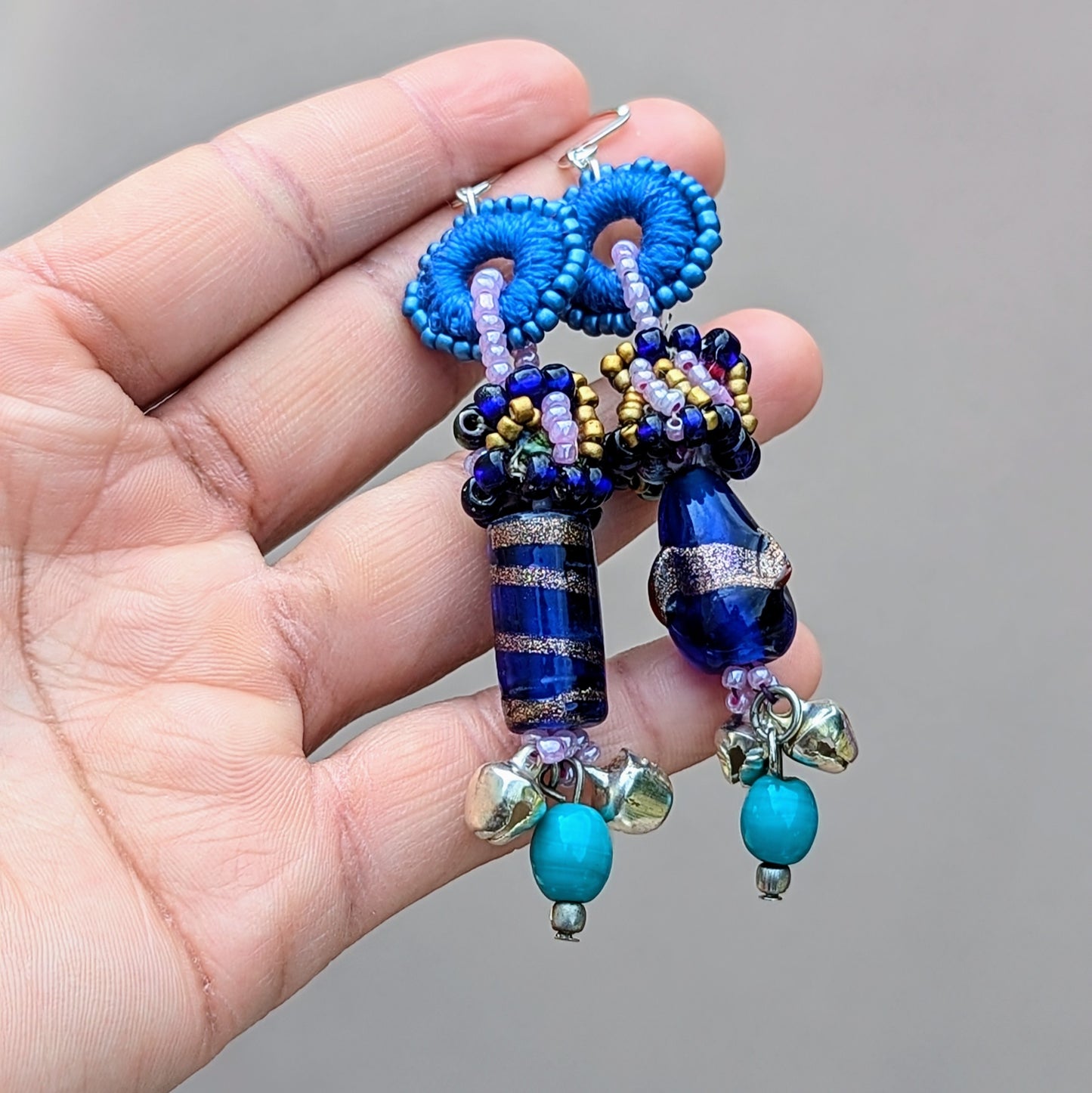 Detail shot highlighting recycled bead composition and fluid asymmetric design.