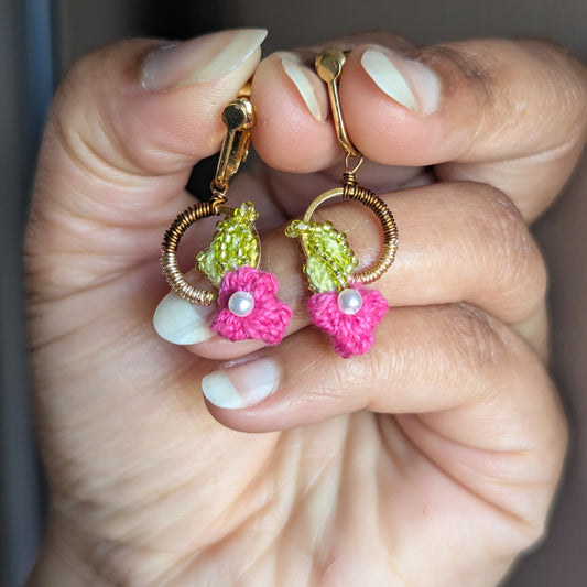 Hand holding a one of a kind pair of Pallavi lightweight comfortable clip on earrings by sustainable luxury brand Mayaani Jewellery UK featuring floral motifs and accents in pink, chartreuse green, pearl and gold.