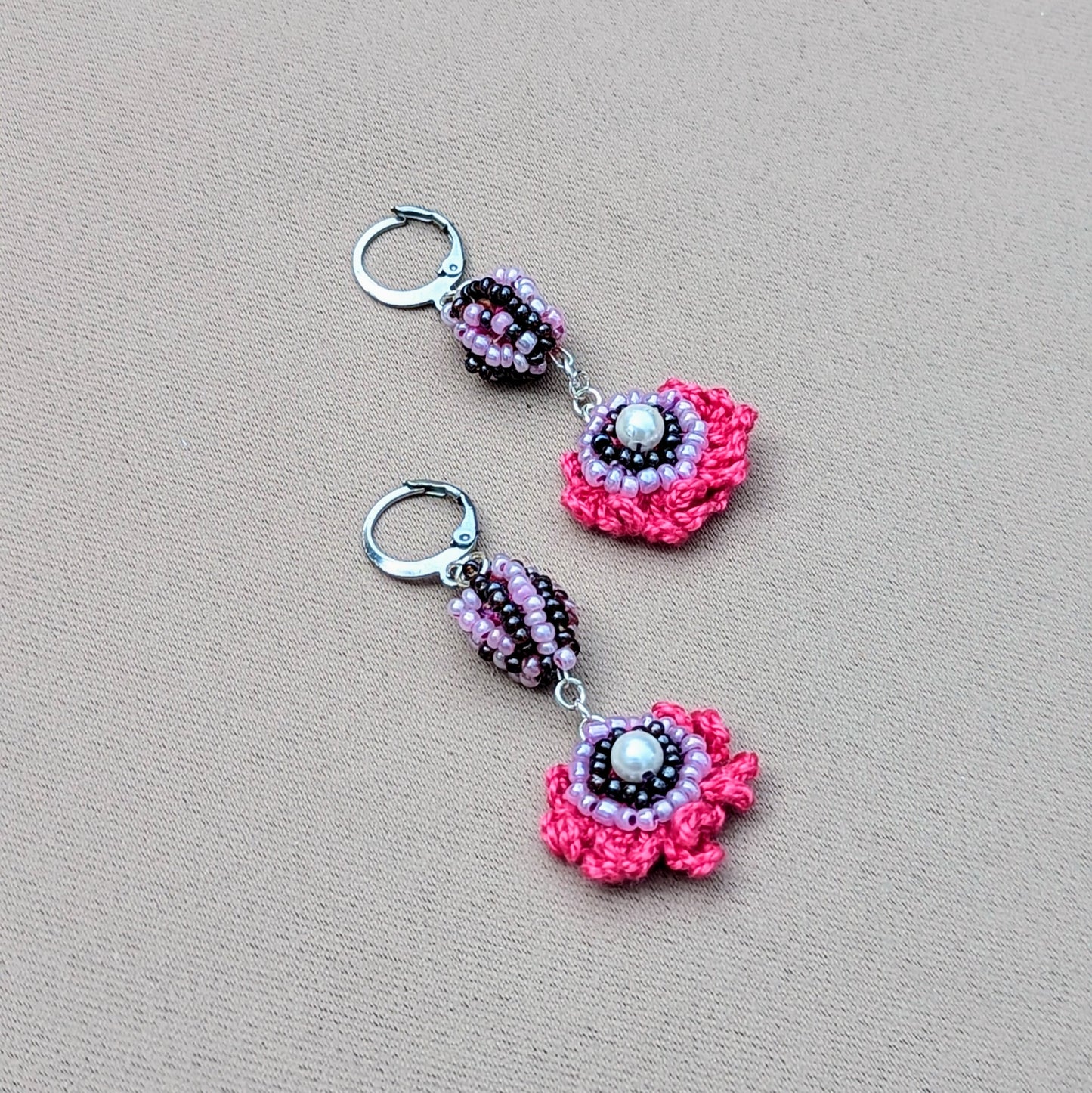 Pair of colourful Mayaani earrings photographed on neutral background highlighting crochet texture.