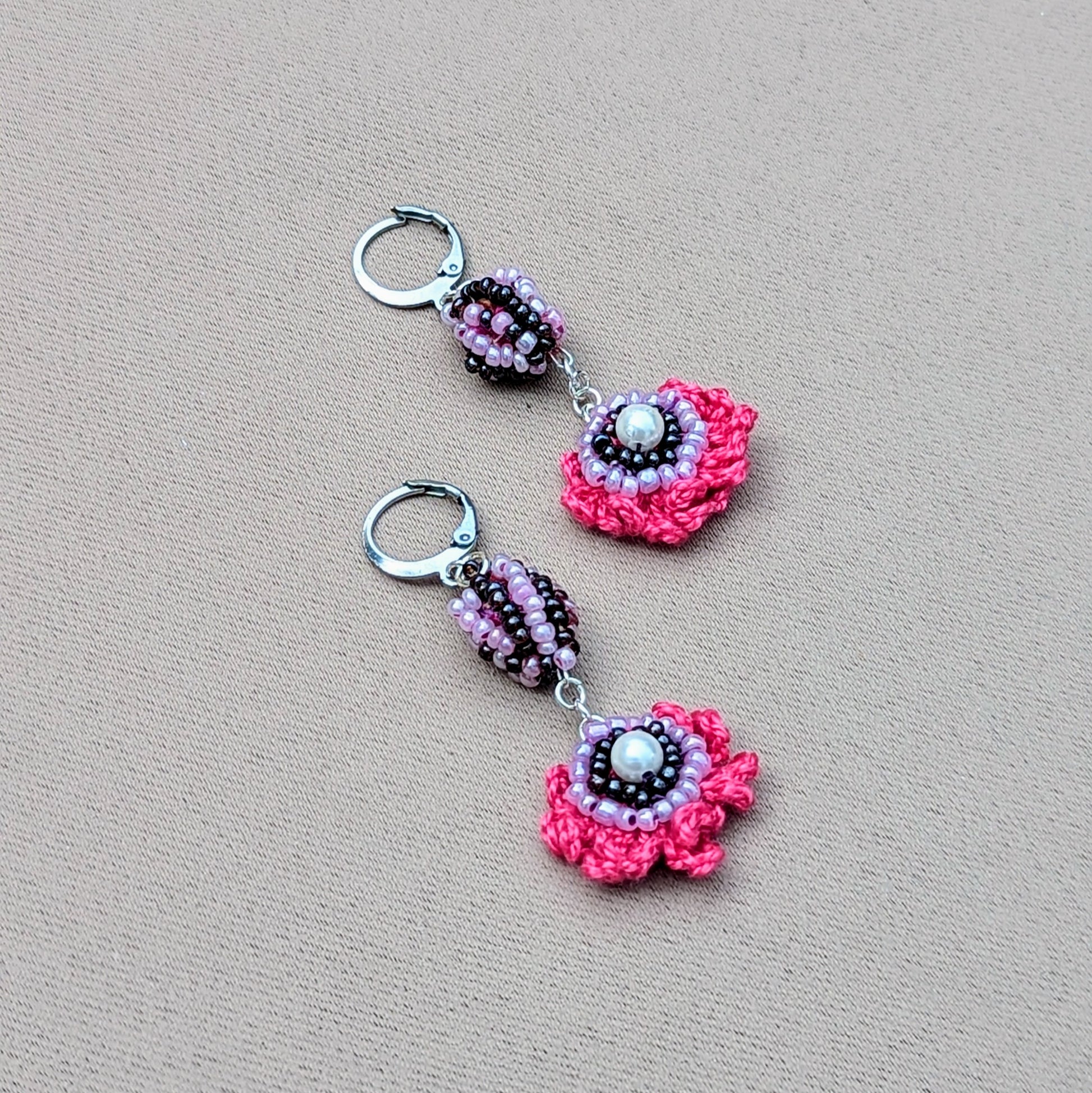Pair of colourful Mayaani earrings photographed on neutral background highlighting crochet texture.