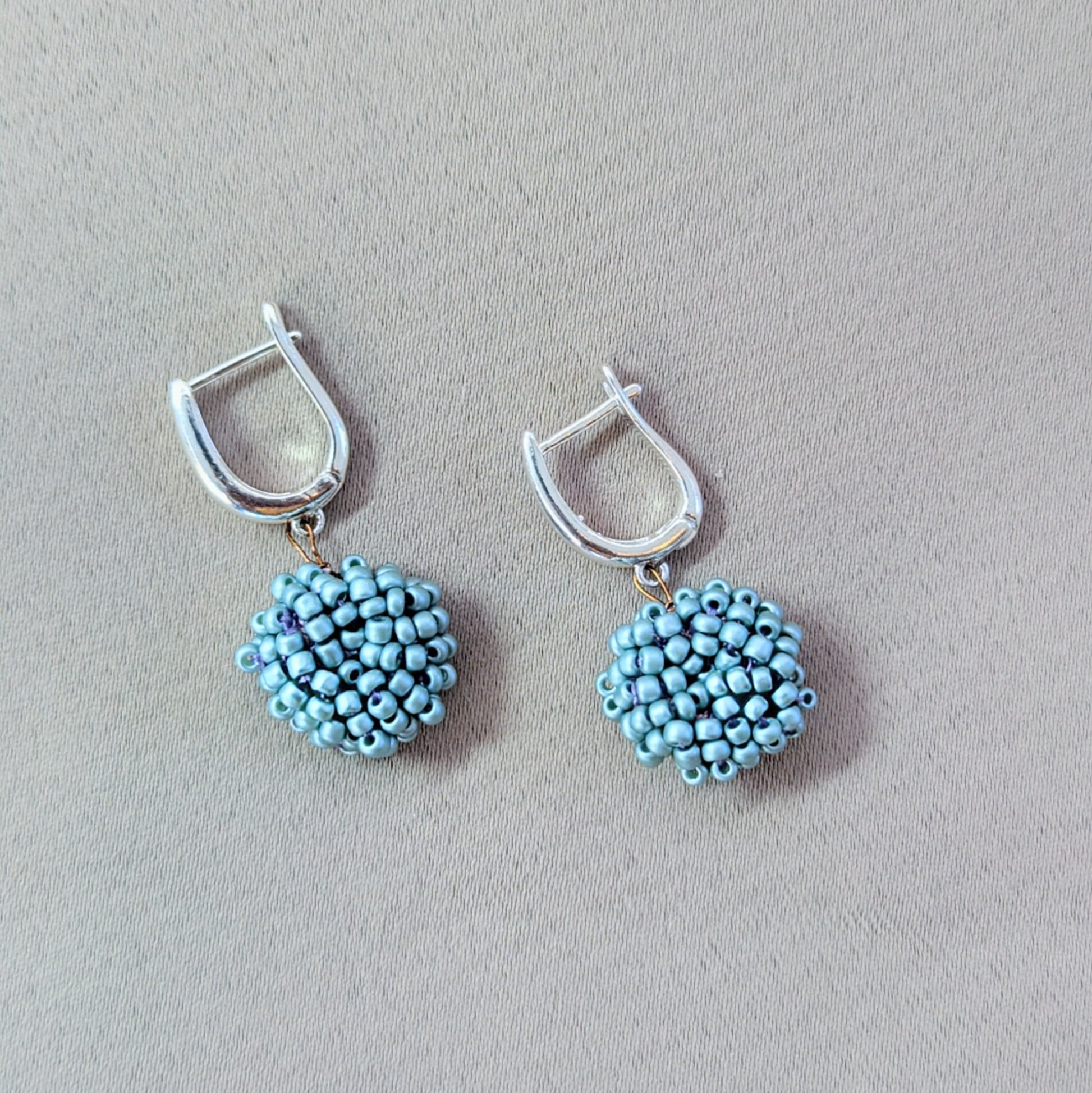 Pair of light blue handmade earrings displayed on neutral background, highlighting their calm tone and smooth texture.
