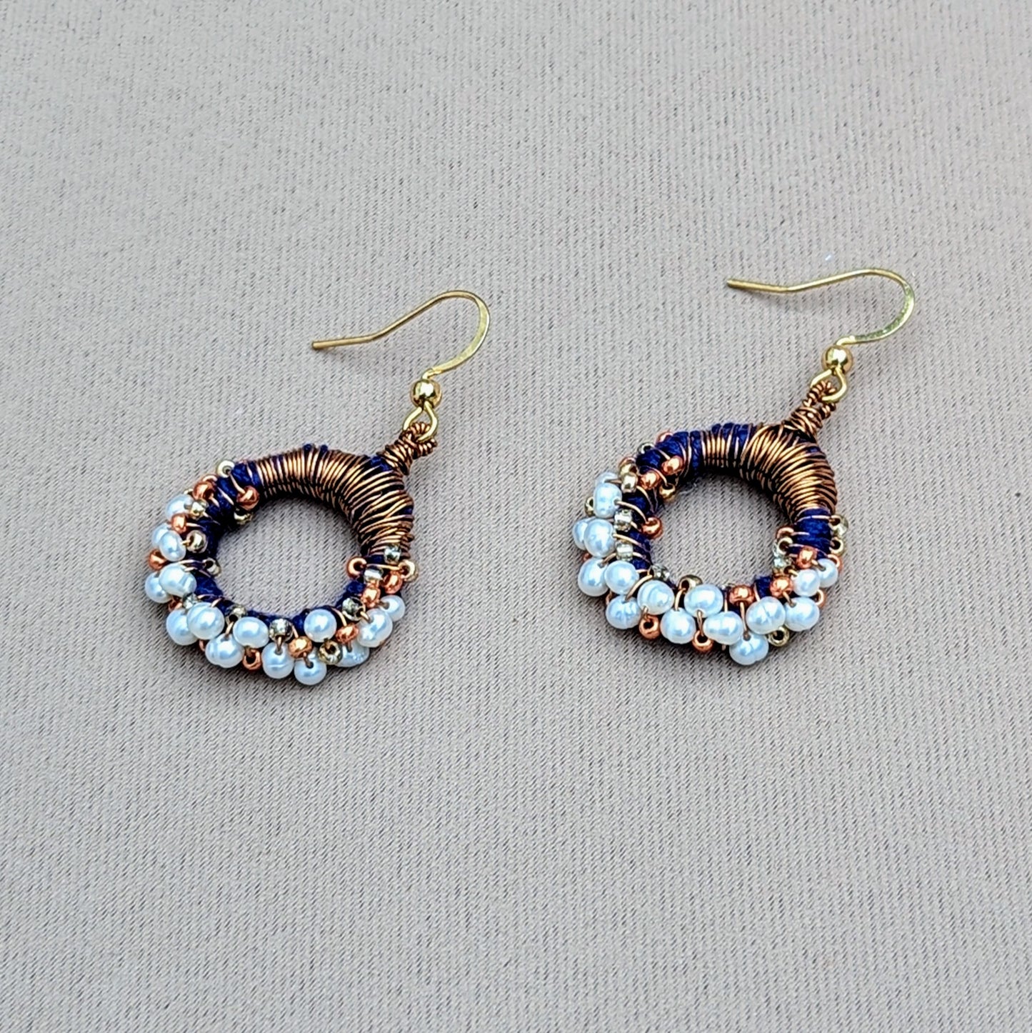 Sustainable handmade earrings with shimmering pearls, copper detailing, and deep blue accents, created by Indian designer Megha.