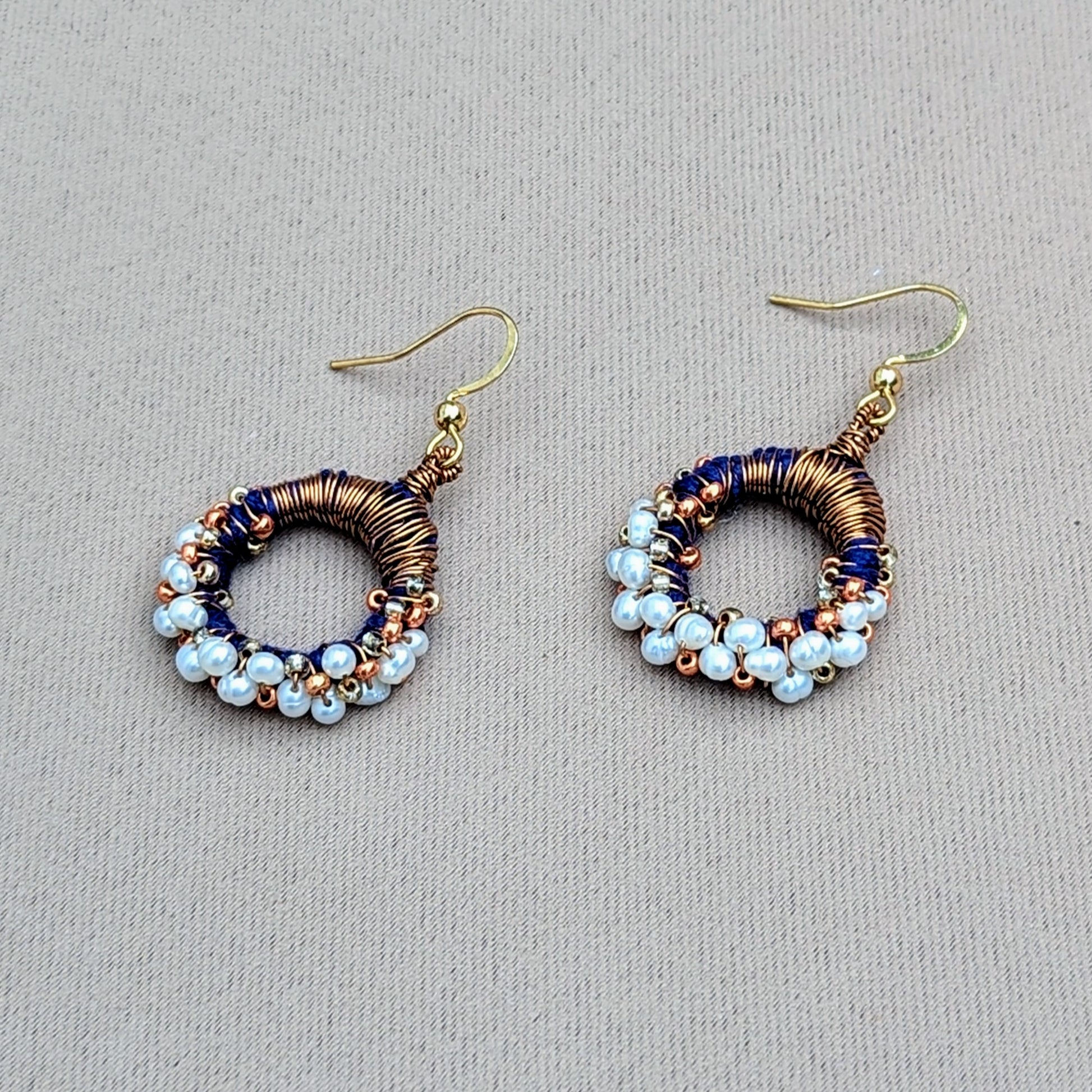 Sustainable handmade earrings with shimmering pearls, copper detailing, and deep blue accents, created by Indian designer Megha.