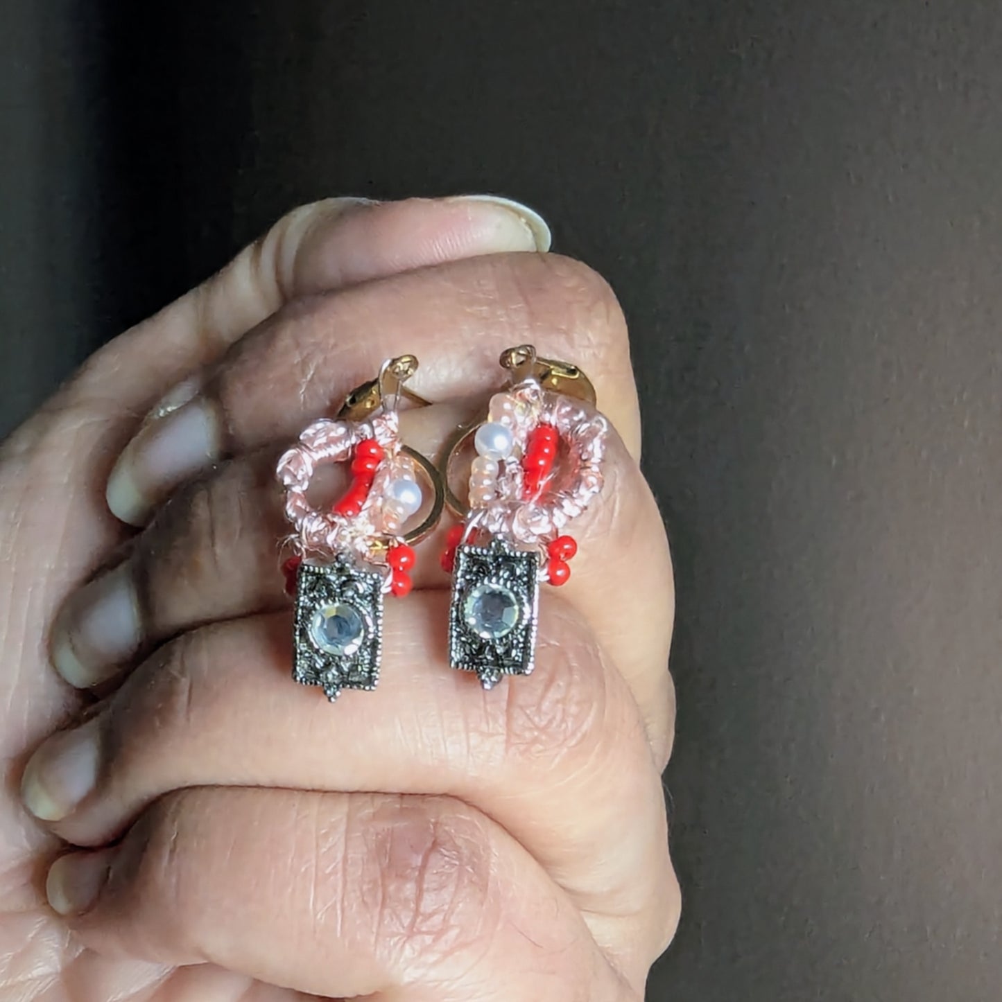 Front view of Inara beaded hoop earrings held gently in hand, featuring glass seed beads, seed pearls and rose gold plated wire with gold hypoallergenic clasps.