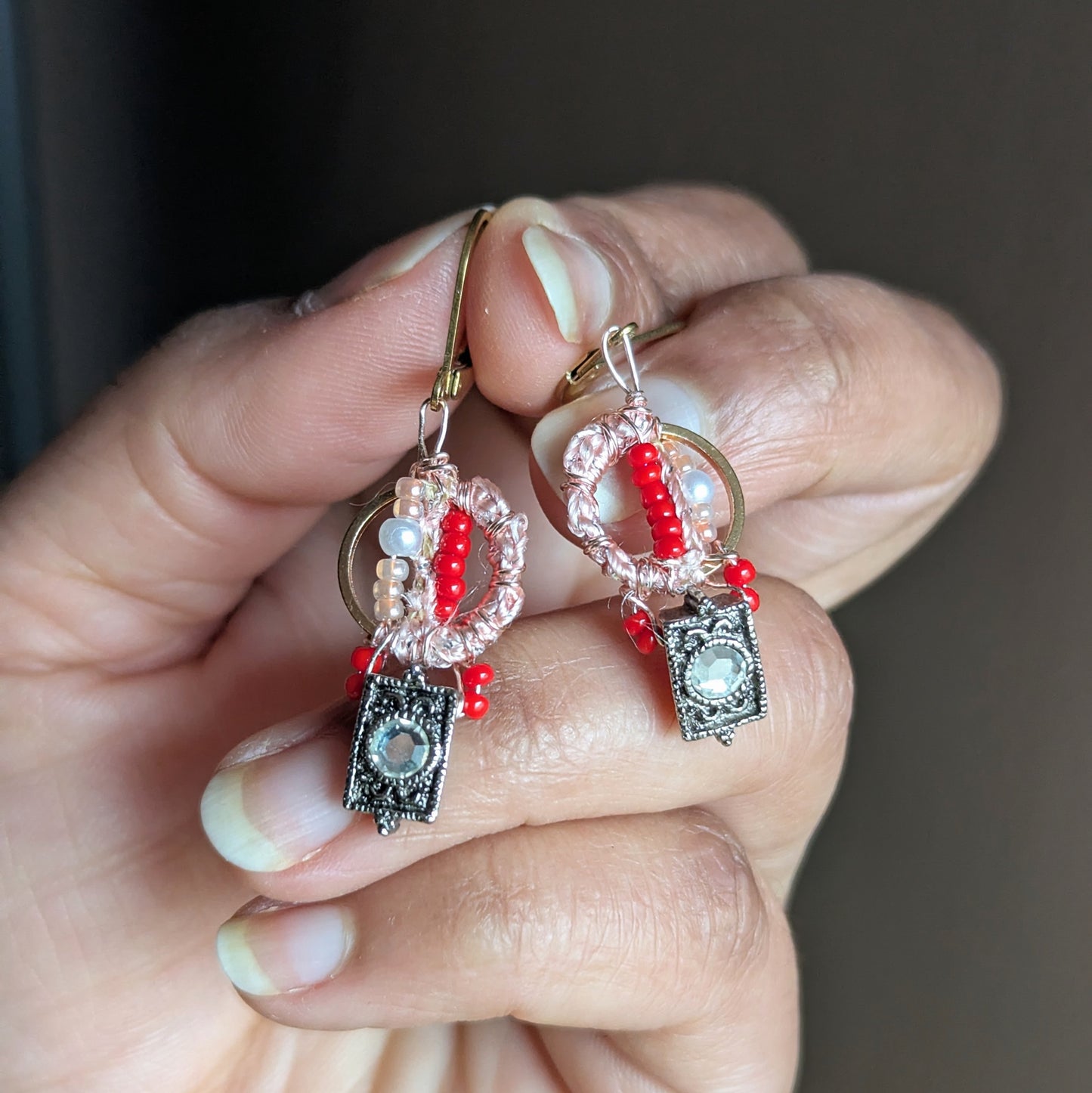Handmade Inara earrings held in hand, front view showing rose gold wire wrapped crochet, vintage cubic zirconia metal beads and gold stainless steel hoops against a soft neutral backdrop.