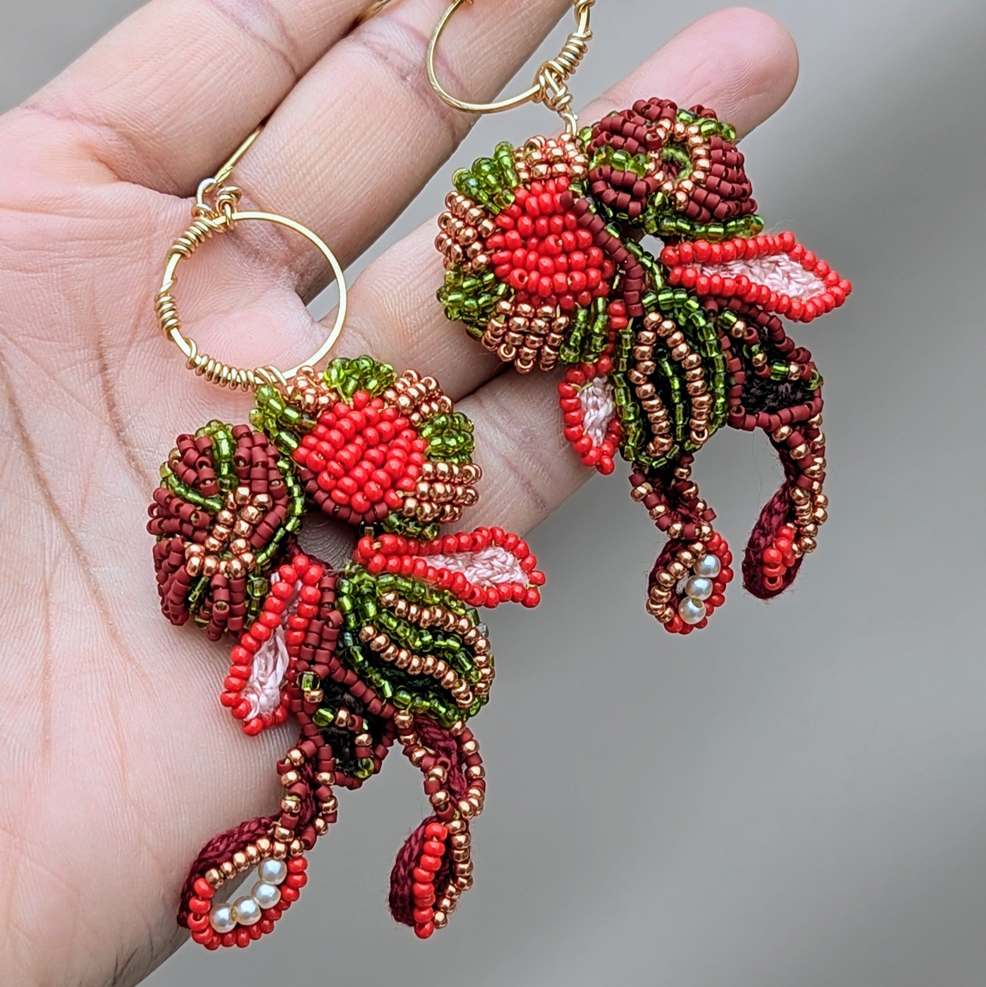 Handmade red and gold Indian bridal statement earrings featuring intricate bead embroidery in a flowing abstract design.