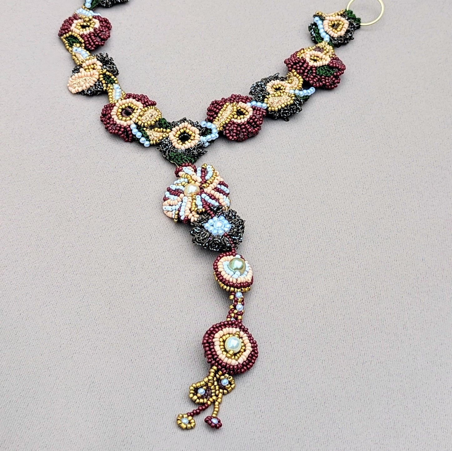 Flat lay view of versatile detachable Aishwarya Indian head piece in red, green and gold with pearl accents handcrafted exclusively for Mayaani Jewellery UK.