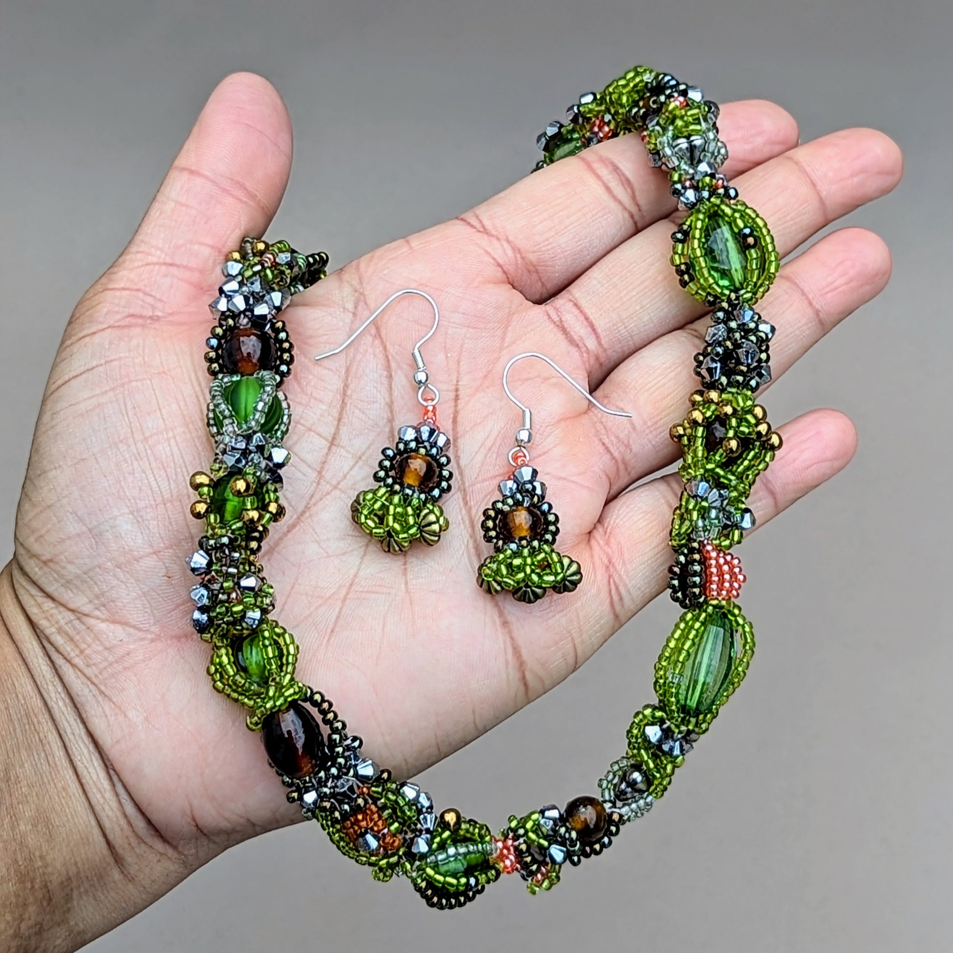 Close-up of forest-inspired beaded necklace with floral silver-plated clasp and sustainable materials.
