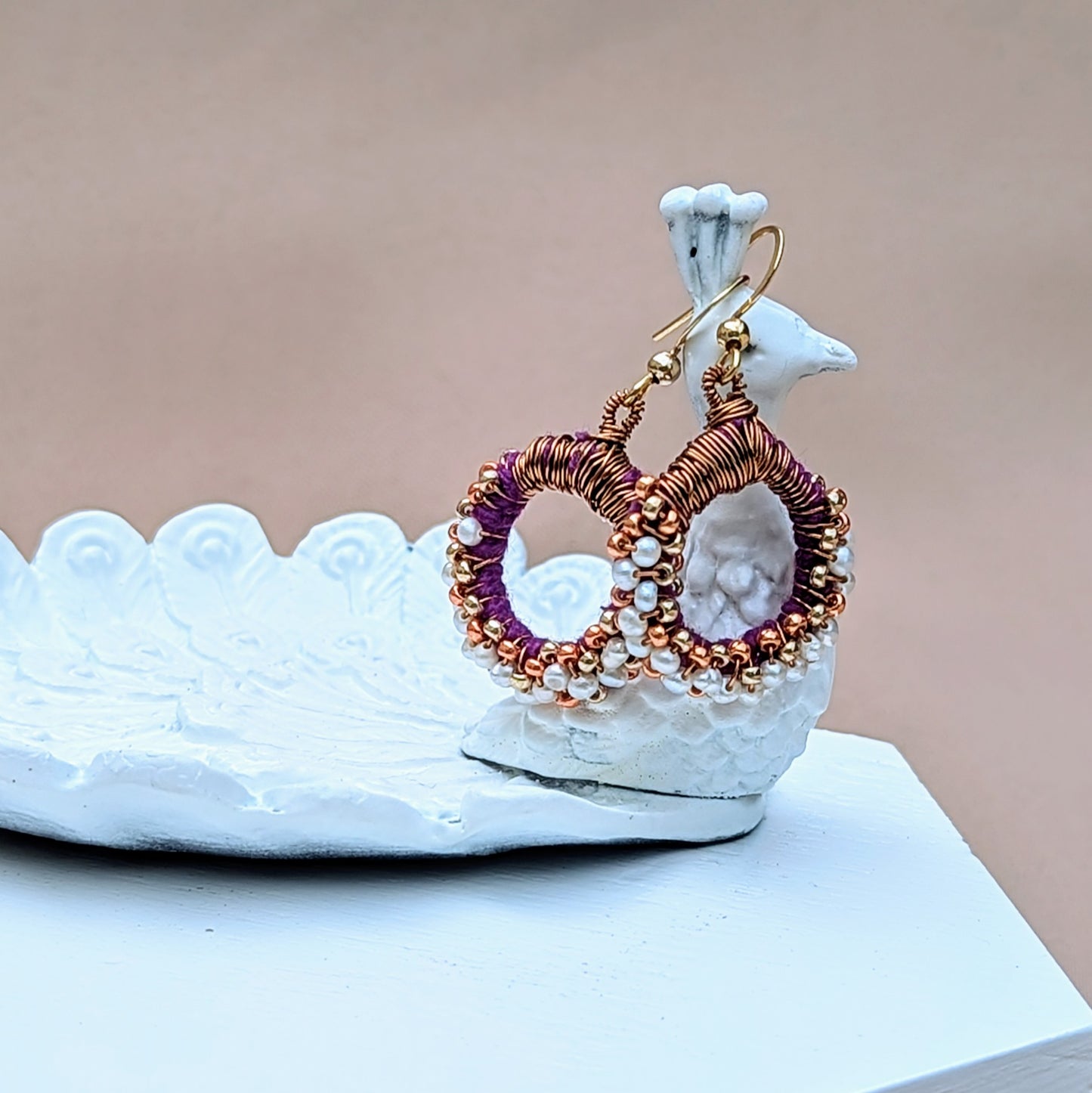 Close-up of sustainably handcrafted purple and pearl earrings with gold plated hooks