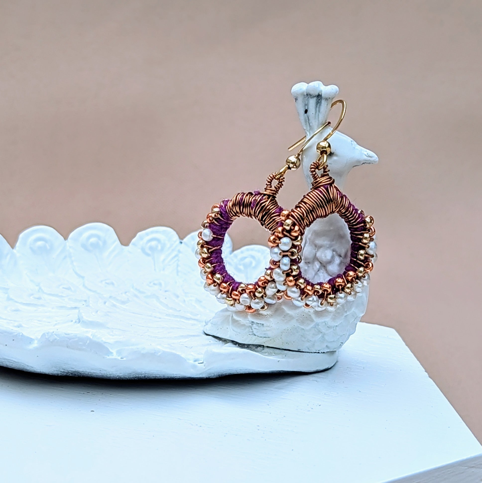 Close-up of sustainably handcrafted purple and pearl earrings with gold plated hooks