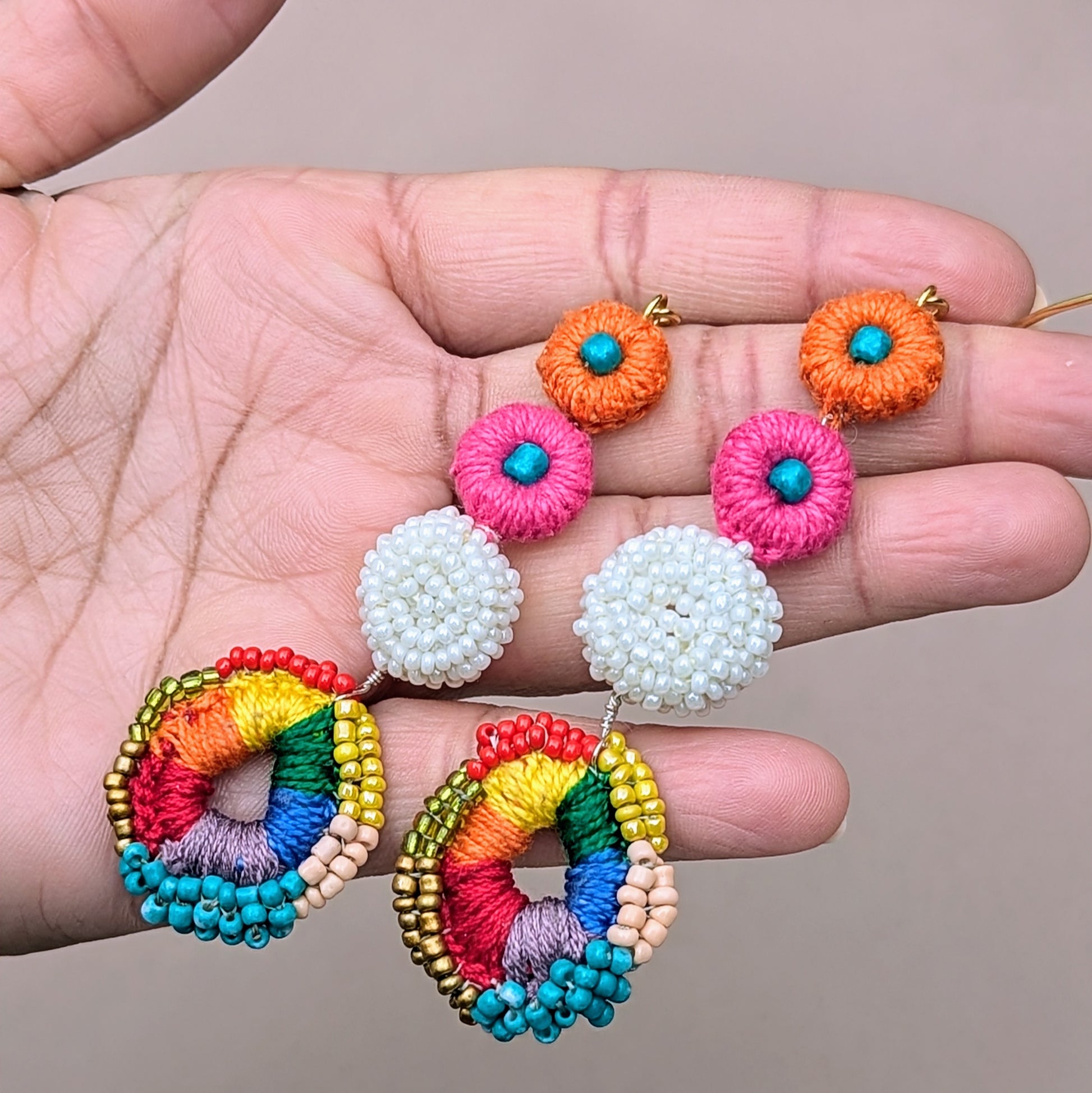 Colourful dangle earrings with layered crochet discs in pink, orange, white, and rainbow - bold, joyful design crafted by UK-based ethical jewellery brand Mayaani.