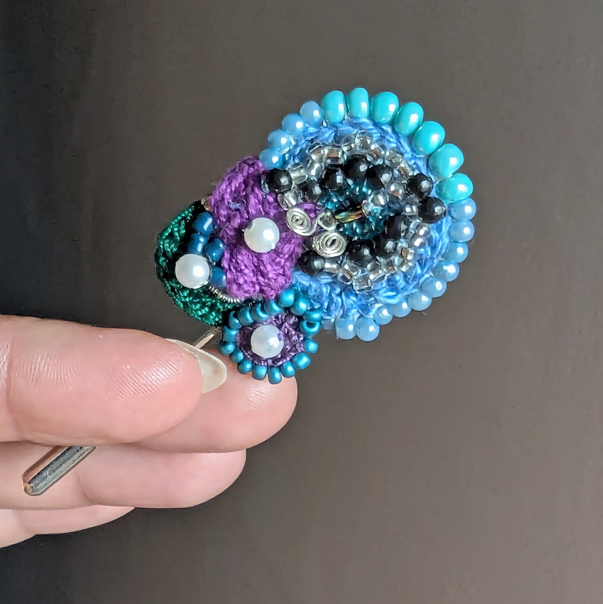 Close-up of Kairavi butterfly brooch showing spiral bead embroidery with silver beads and seed pearl accents.
