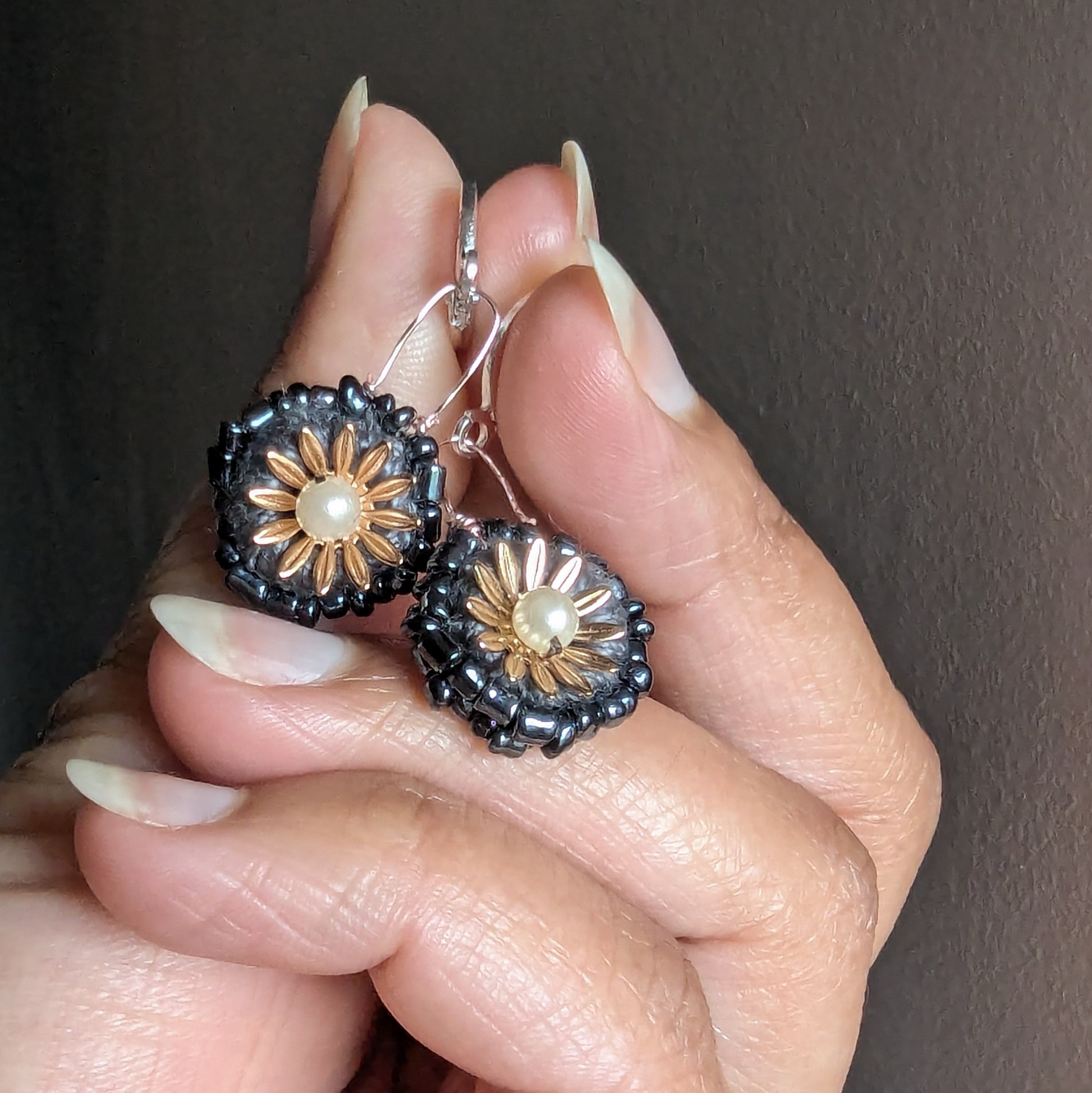 Hand holding elegant grey beaded earrings handmade for Mayaani with vintage upcycled glass beads and seed pearls.