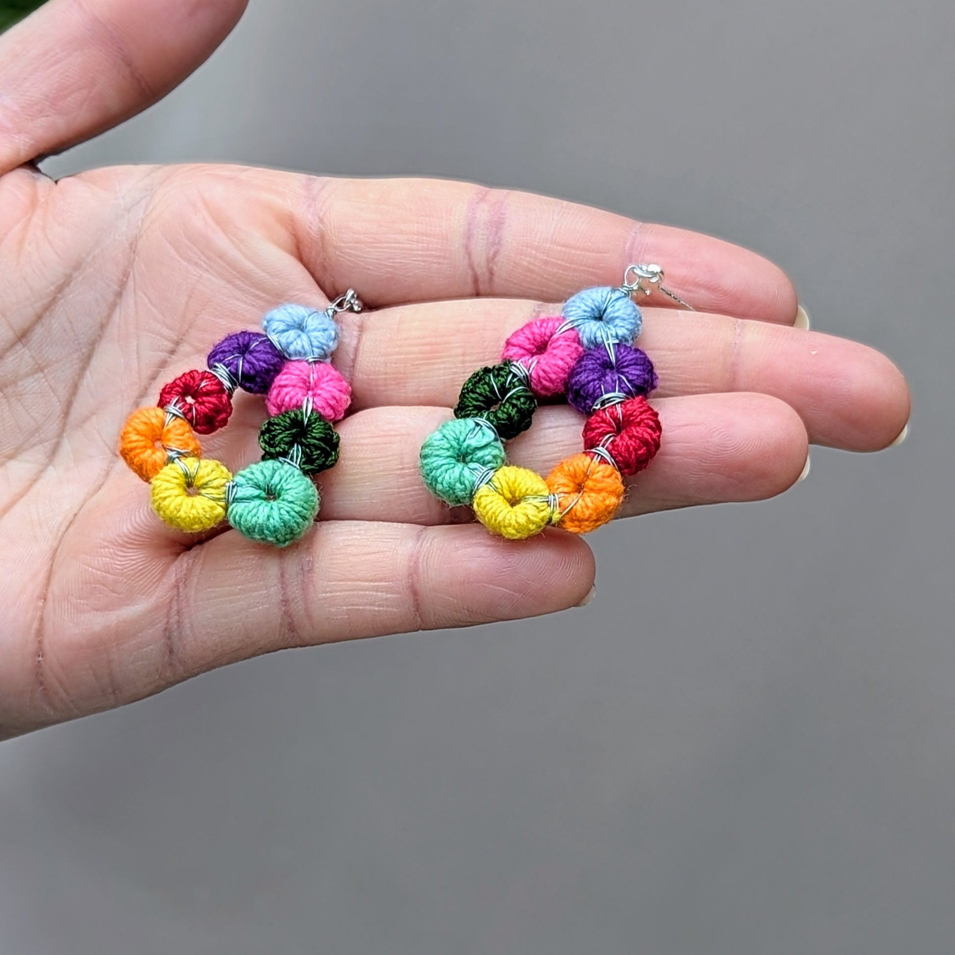 Hope Springs Ratna rainbow diamond-shape crochet earrings, handmade in the UK with sustainable materials, photographed in hand.