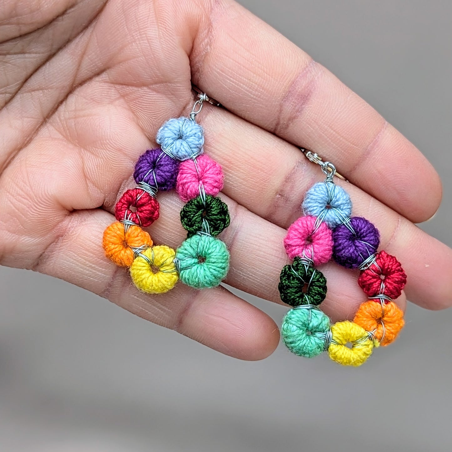 Close-up of Komali Hope Springs earrings showing multicolour crochet circles and silver-toned wire wrapping.