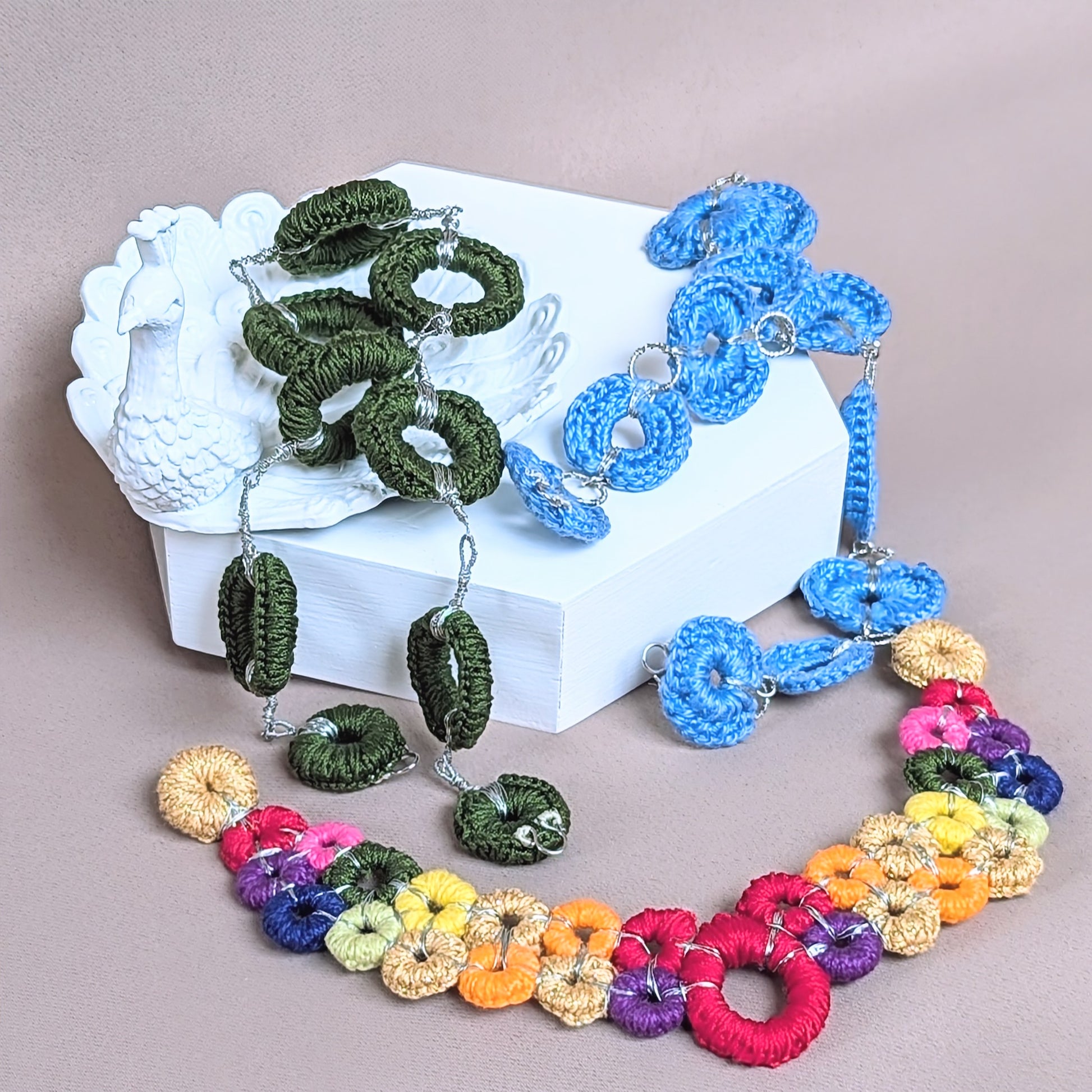 One-of-a-kind rainbow beaded necklace with detachable centrepiece displayed on neutral backdrop, handmade in the UK using crochet and wire wrapping.