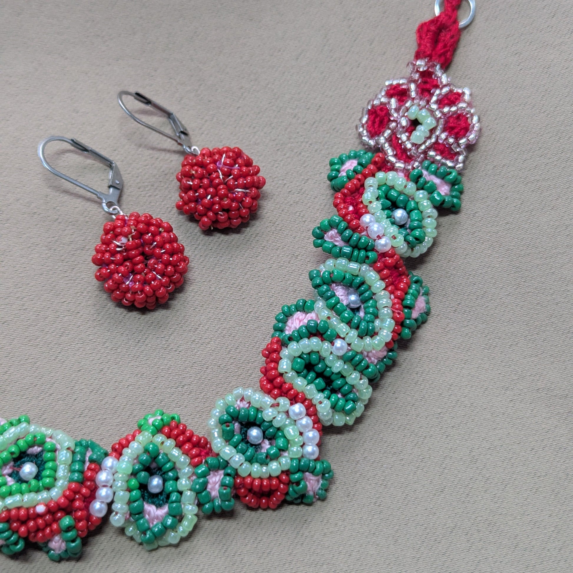 Close-up of Malika bracelet and matching cluster earrings in red, green, pink, pearl and silver tones.
