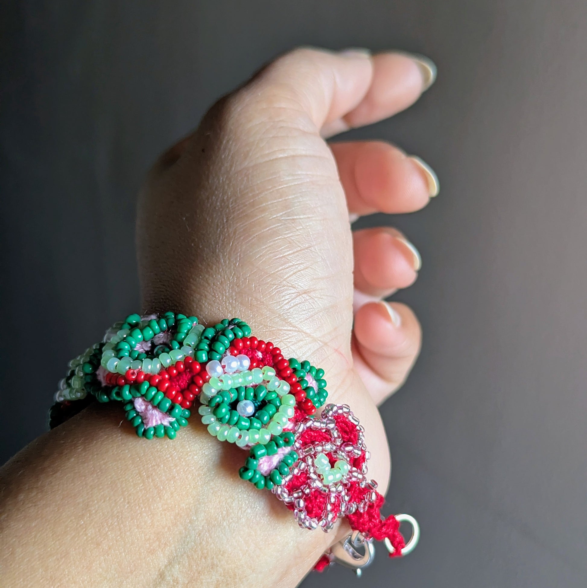 Side view of green, red and rani pink bracelet highlighting crochet and bead-woven motifs.