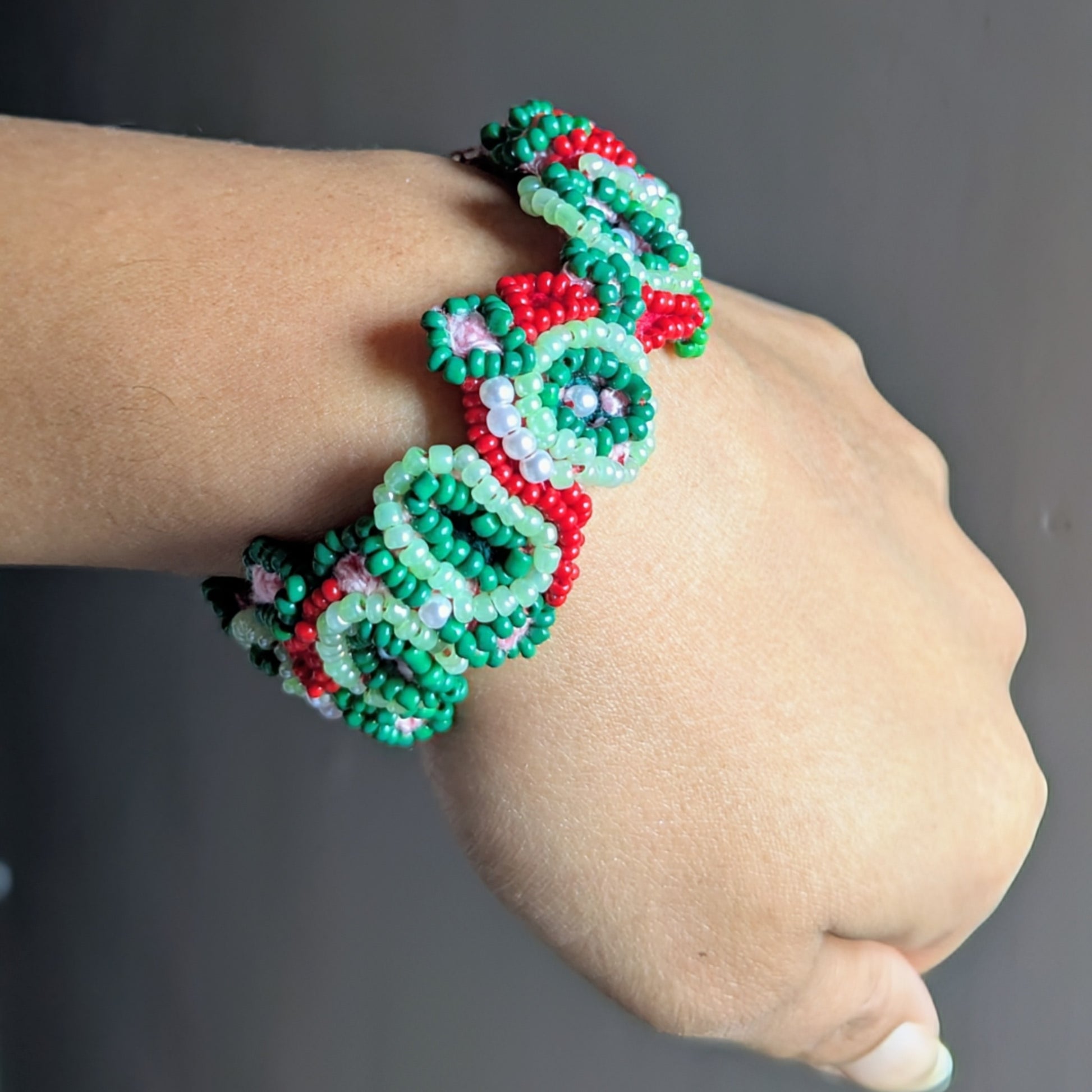 Close up view of a statement designer woven red and green bracelet sustainably handcrafted exclusively for Mayaani Jewellery UK.