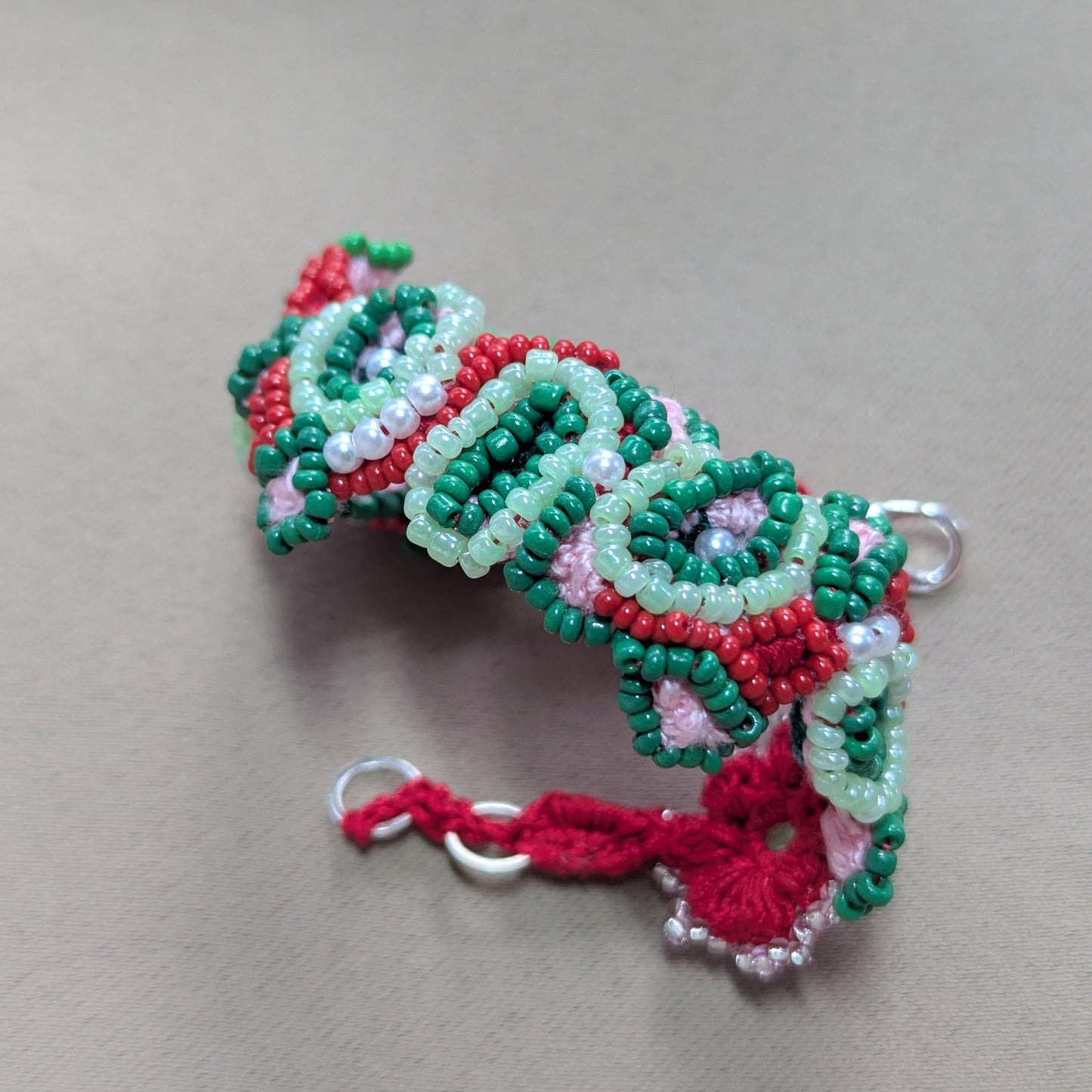 Handmade green, red & pink statement bracelet with silver plated clasp photographed against neutral background.