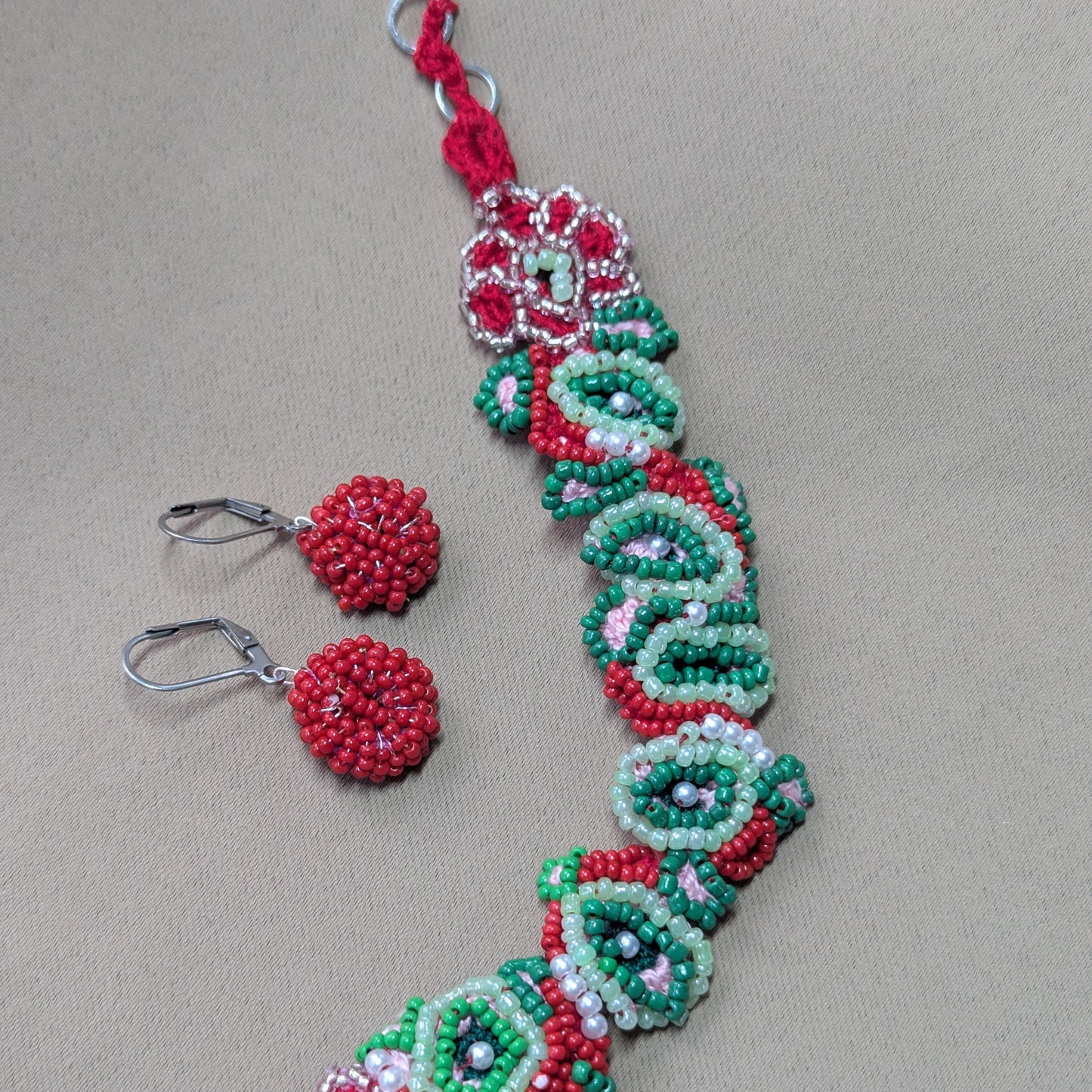 Close-up of Malika bracelet and matching cluster earrings in red, green and pearl tones.