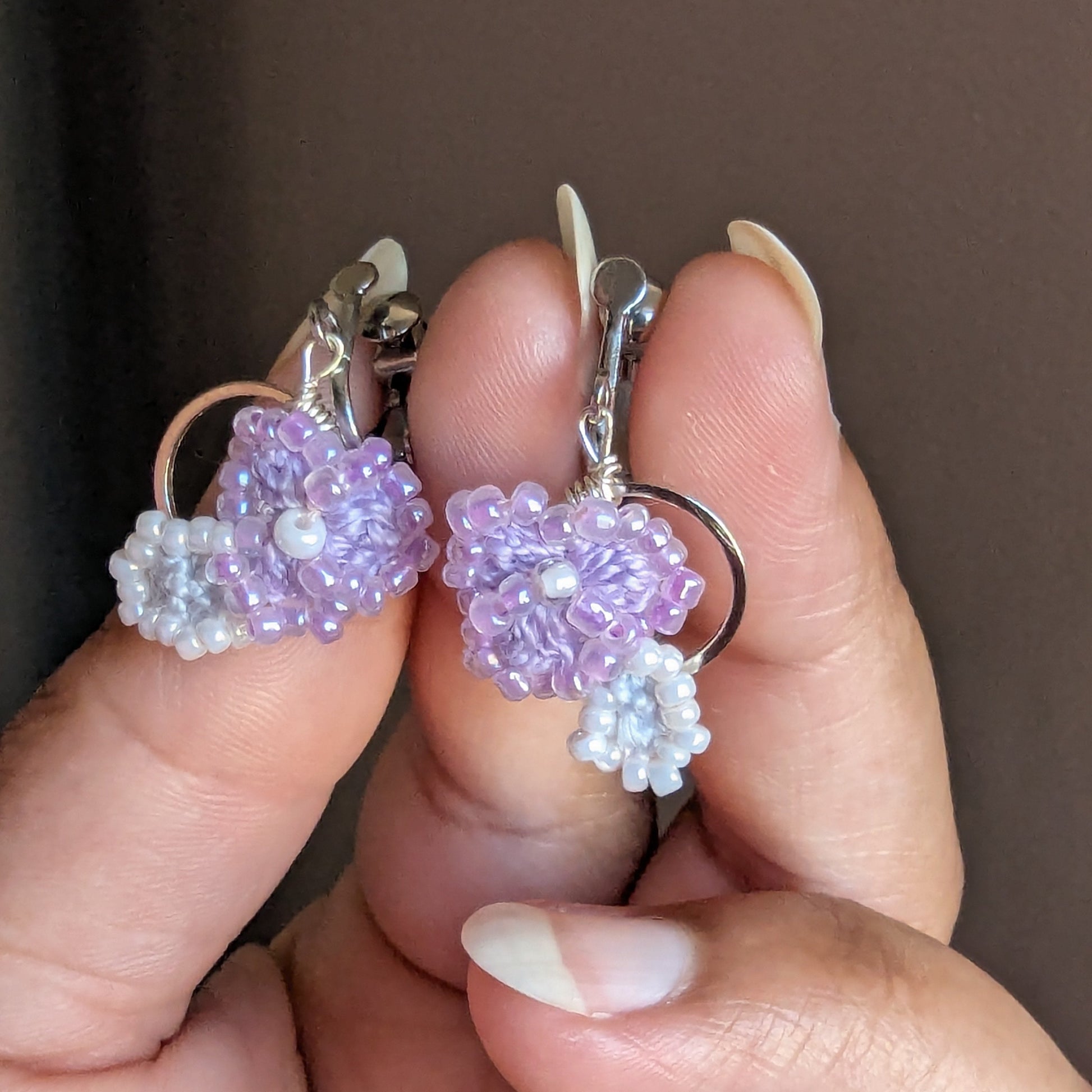 Hand holding a lightweight delicate pair of Malti clip-on earrings exclusively created for sustainable UK brand Mayaani Jewellery.