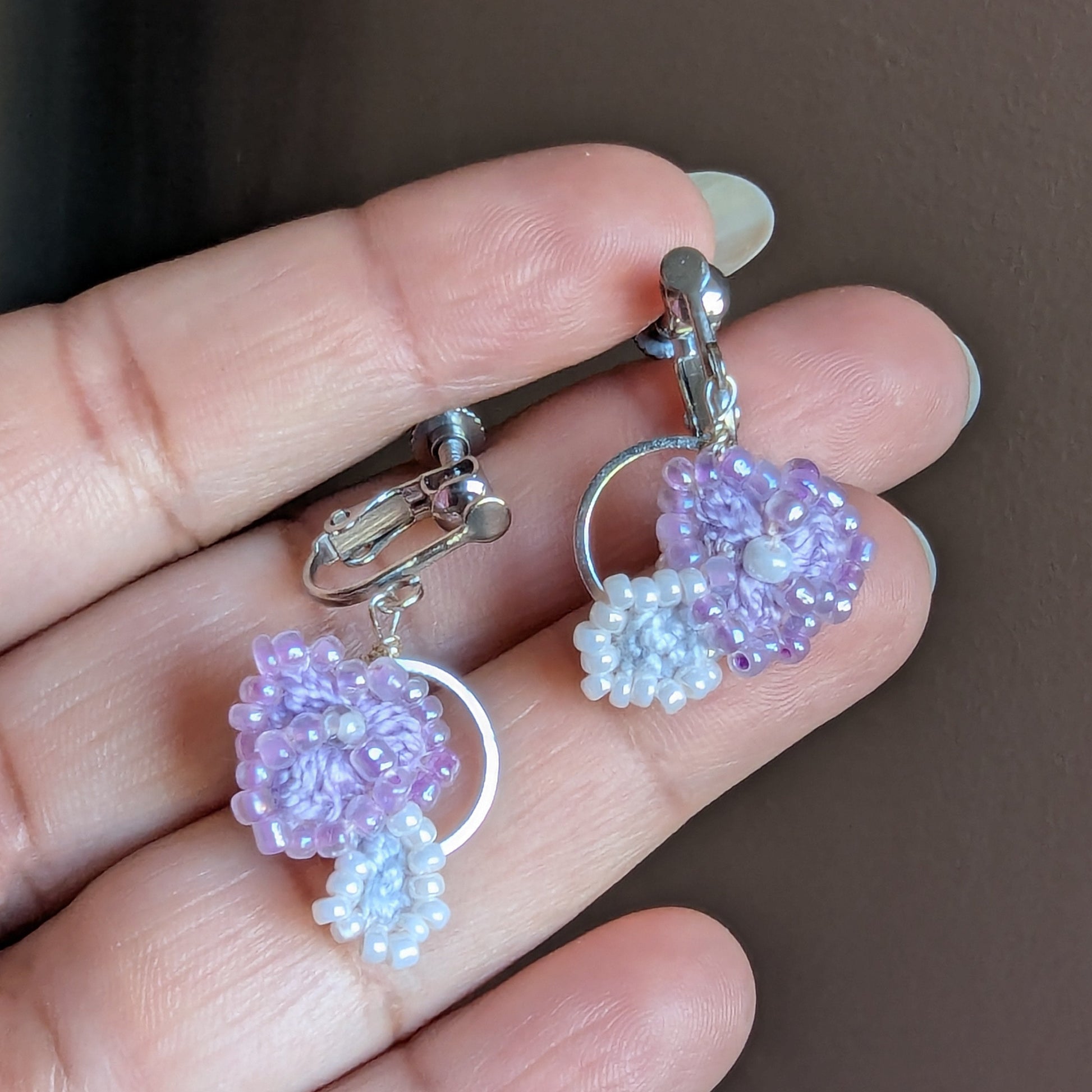 Close-up of Malti clip-on earrings held in hand showcasing adjustable stainless steel screw back clasps for added comfort for non-pierced ears.