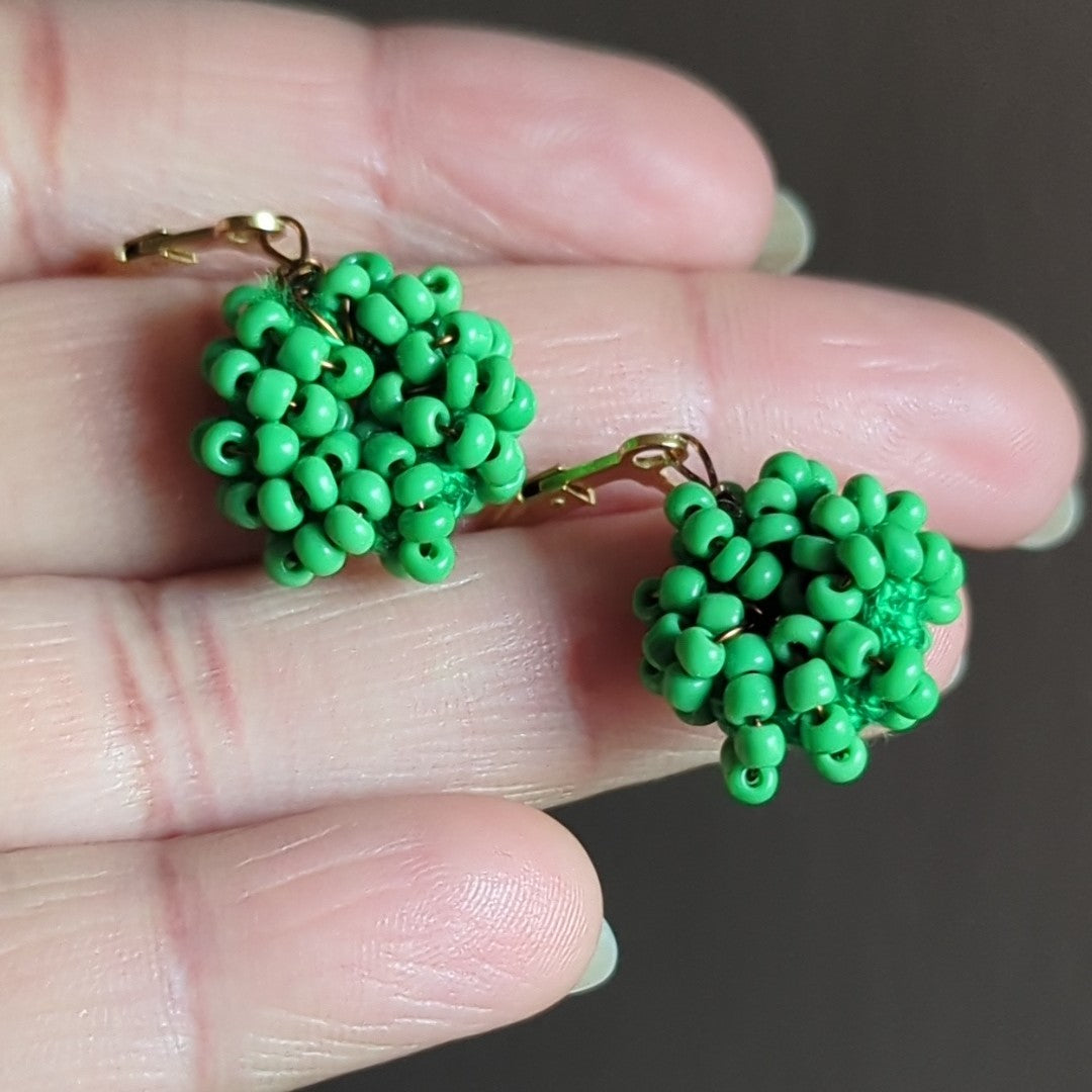Close-up of artisan-made light green beaded earrings with gold clasps.