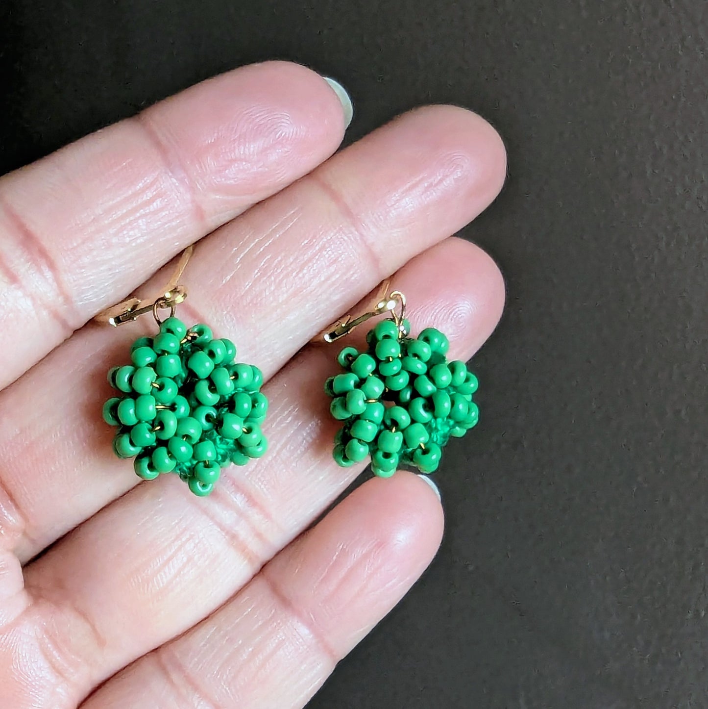 Vibrant light green hoop-style earrings woven with glass seed beads, antique bronze wire, and gold clasps for an elegant handmade finish.