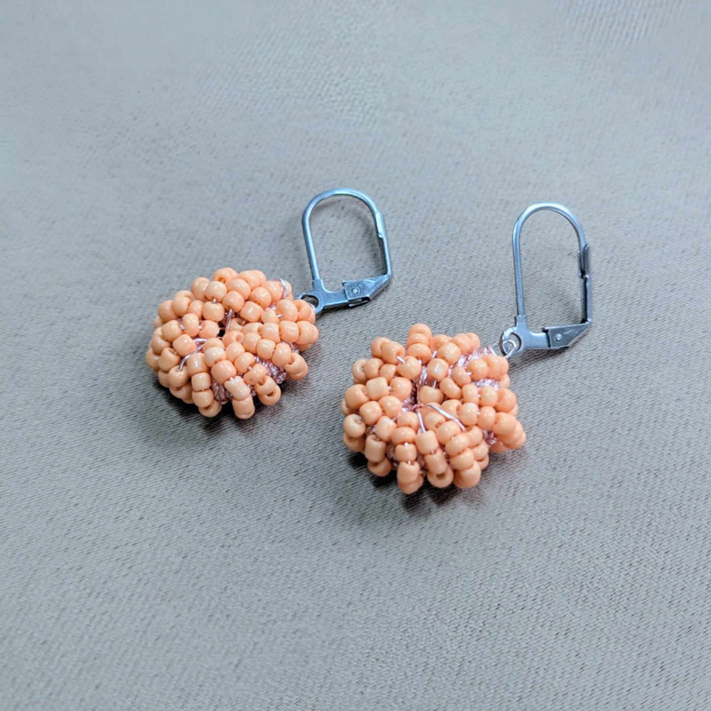 Sustainable handmade earrings in warm peach tones with fine gold detailing.