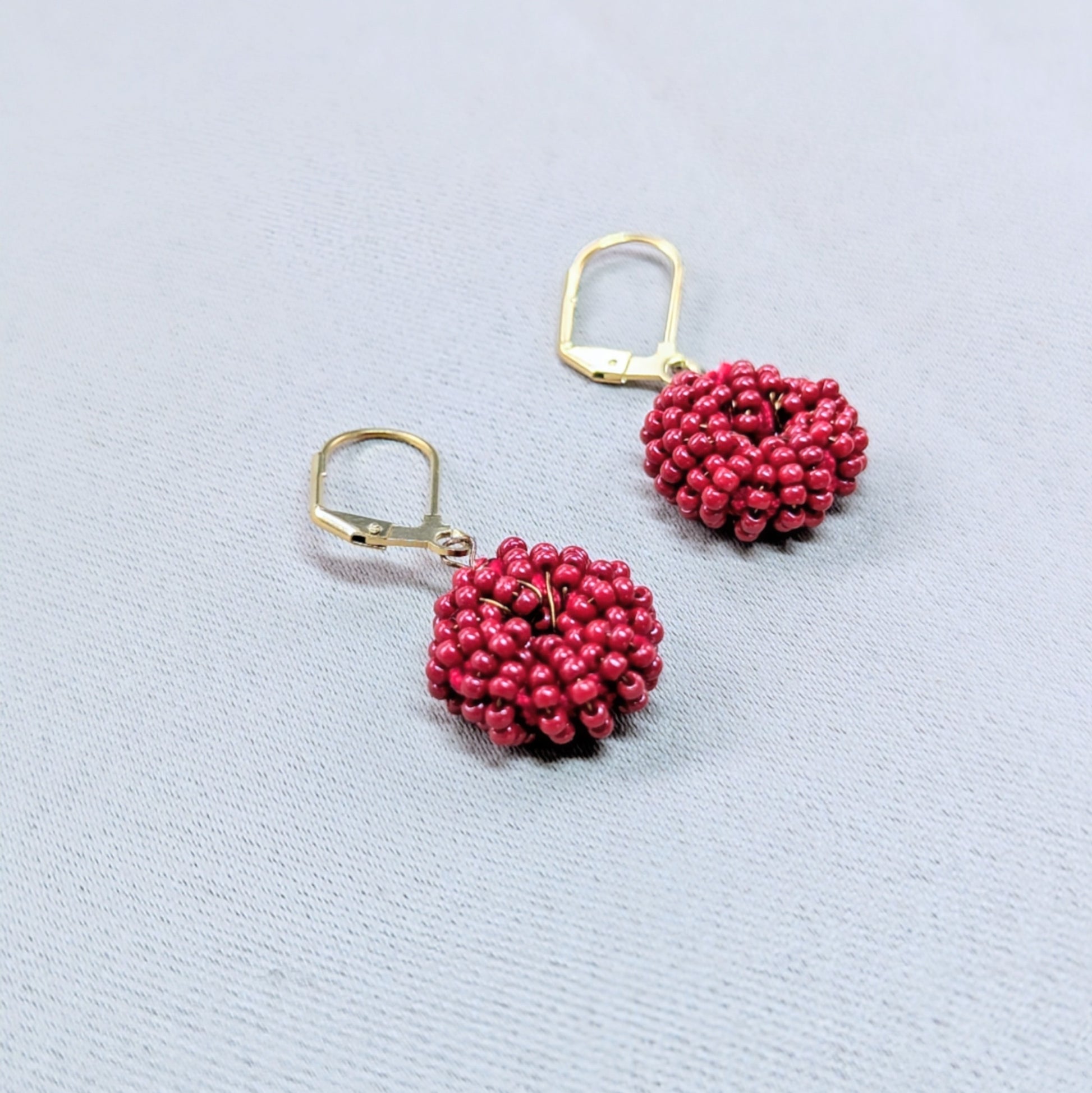 Handmade red beaded hoop shape earrings sustainably crafted with antique bronze and gold tones.