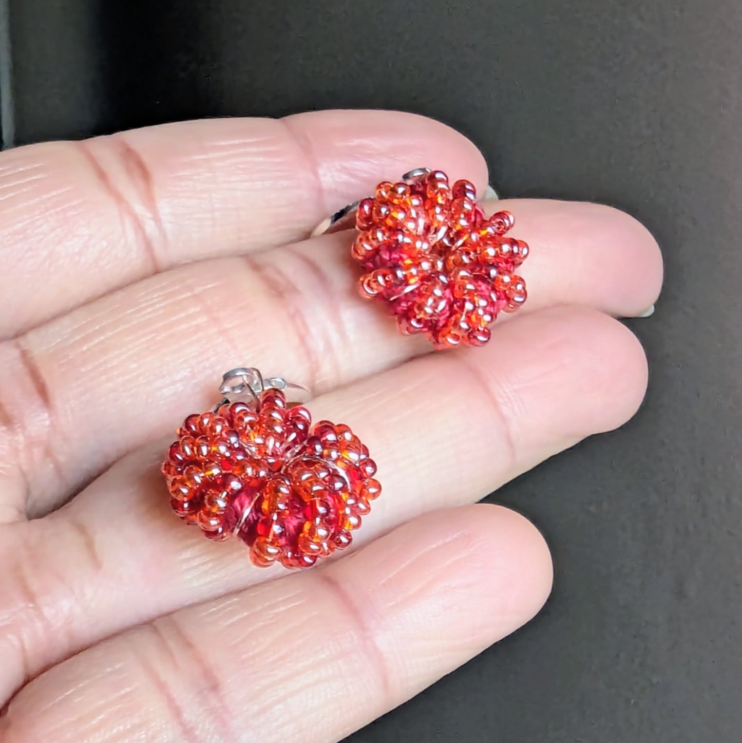 Sustainable handmade earrings glowing with orange-red glass beads.