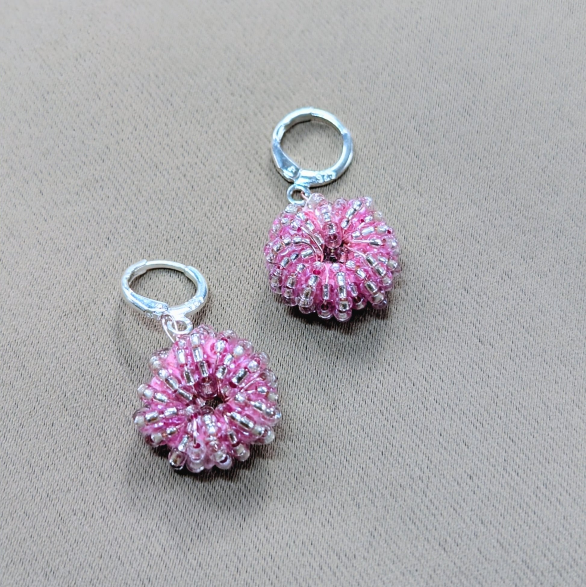 Close-up of artisan-made pink beaded earrings with sterling-silver clasps.